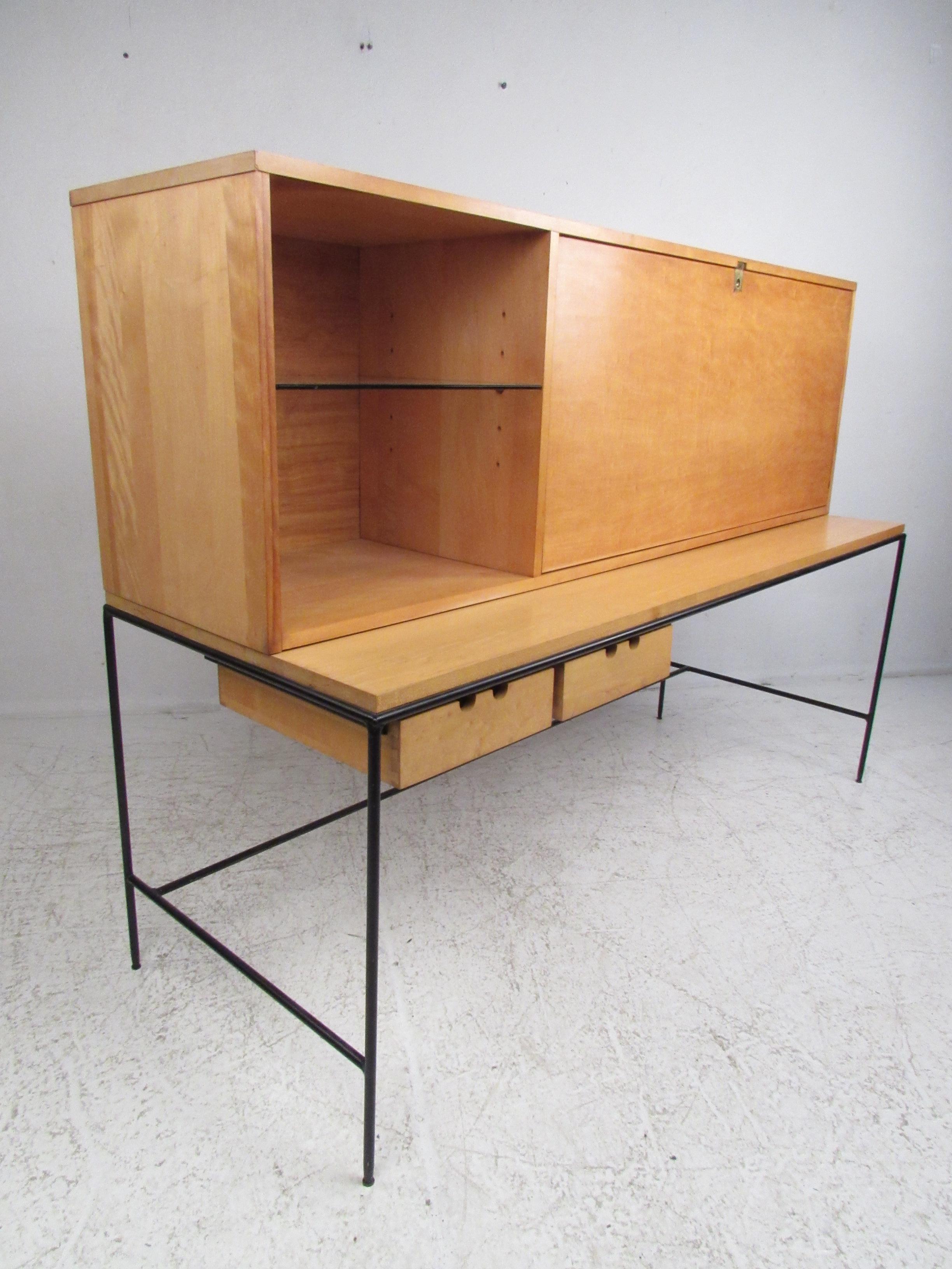 This beautiful vintage modern desk features an enameled steel frame and a maple casing. A stylish design that boasts a large drop front hiding a large compartment and drawers for storage. This rare two-piece desk offers plenty of work space without