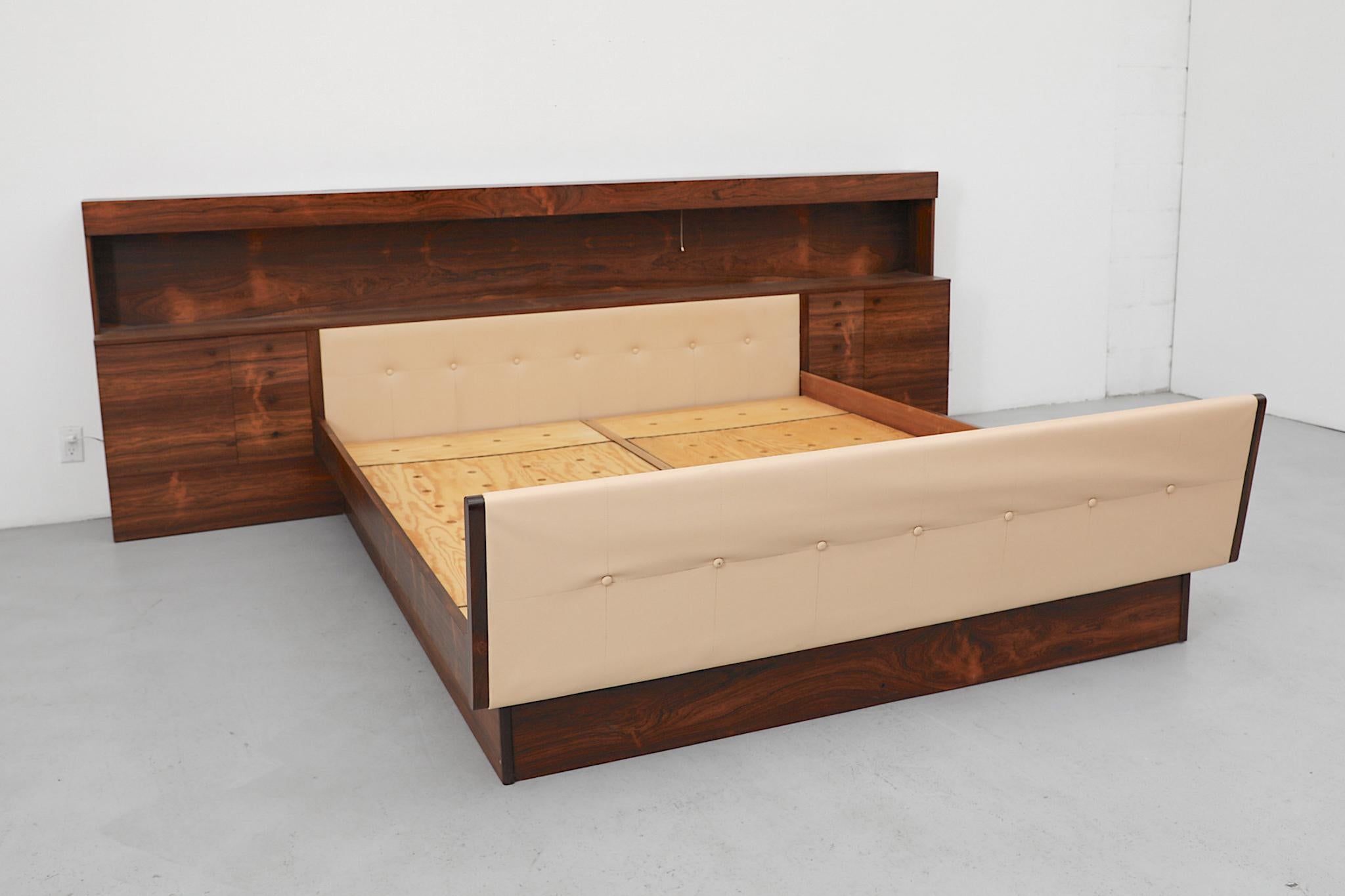 Lit double en bois de rose danois du milieu du siècle. Exemple étonnant du design scandinave d'après-guerre, ce lit est équipé de tables de nuit intégrées, d'une tête de lit et d'un pied de lit touffetés de couleur crème, d'une étagère intégrée et