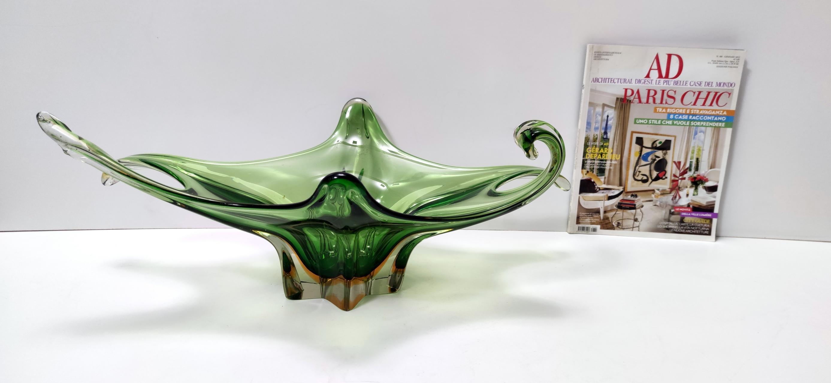 Italy, 1960s. 
This bowl/centerpiece is made in green Murano glass with slight shades of orange. 
It is a vintage piece, therefore it might show slight traces of use, but it can be considered as in perfect original condition and ready to become a