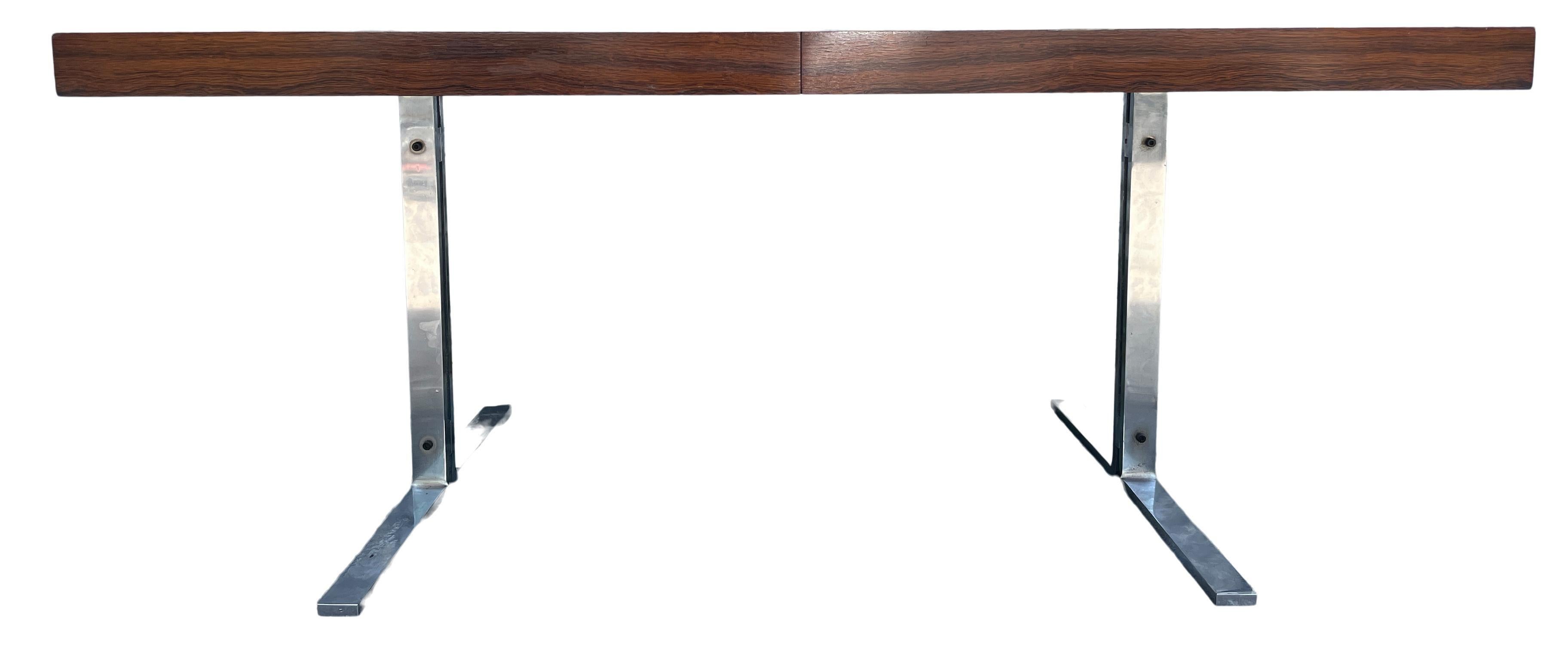 Magnifique table de salle à manger rare en palissandre brésilien avec un plateau de forme rectangulaire sur des pieds chromés. La table de salle à manger comporte un abattant amovible qui se range sous la table. La feuille est un peu plus foncée car