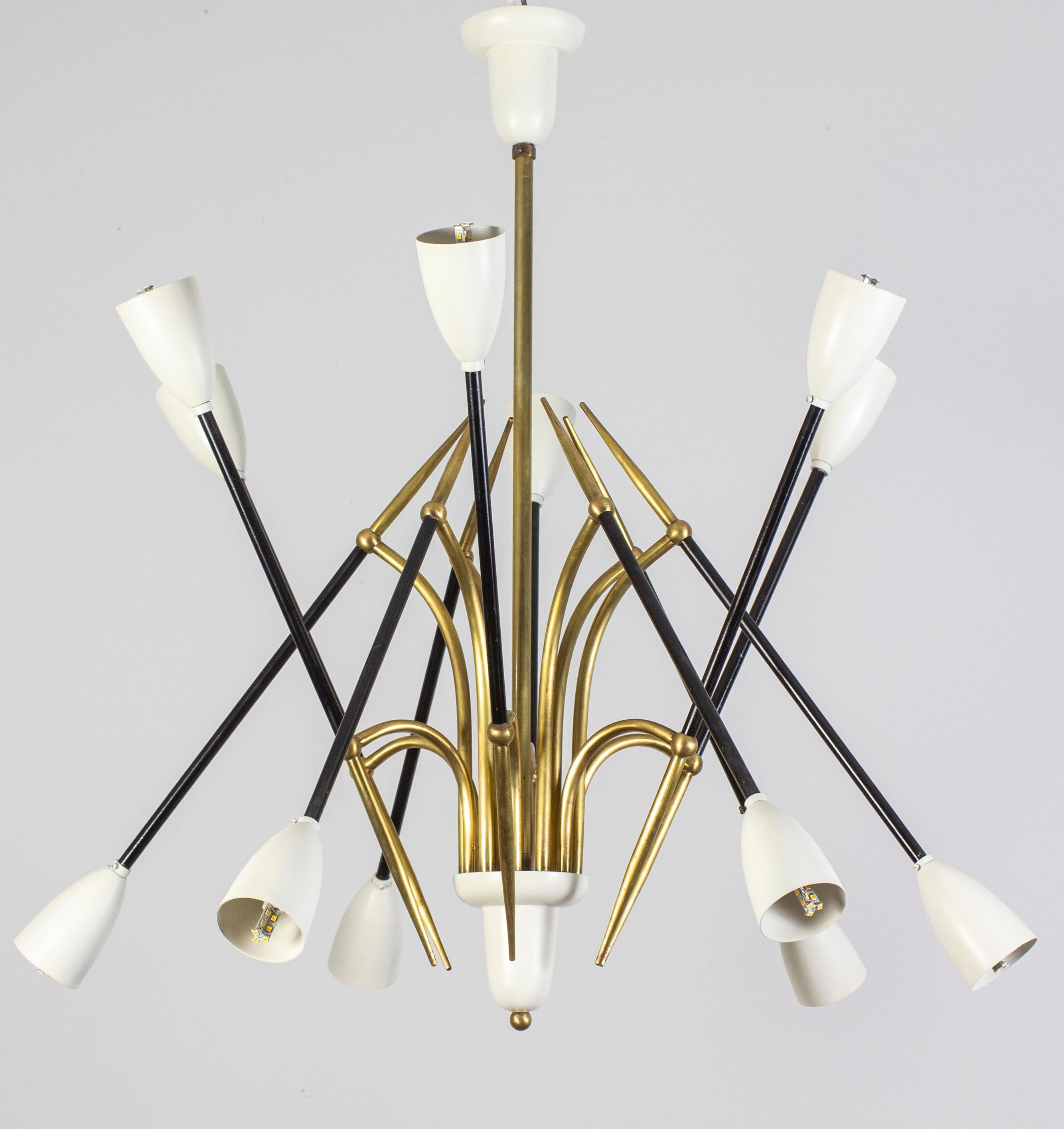 Singular  Stilnovo chandelier, features 12 arms, each supporting the ivory lacquered shades.
Elegant brass central frame.
This chandelier is in excellent original condition and we can rewire to U.S. standards.
