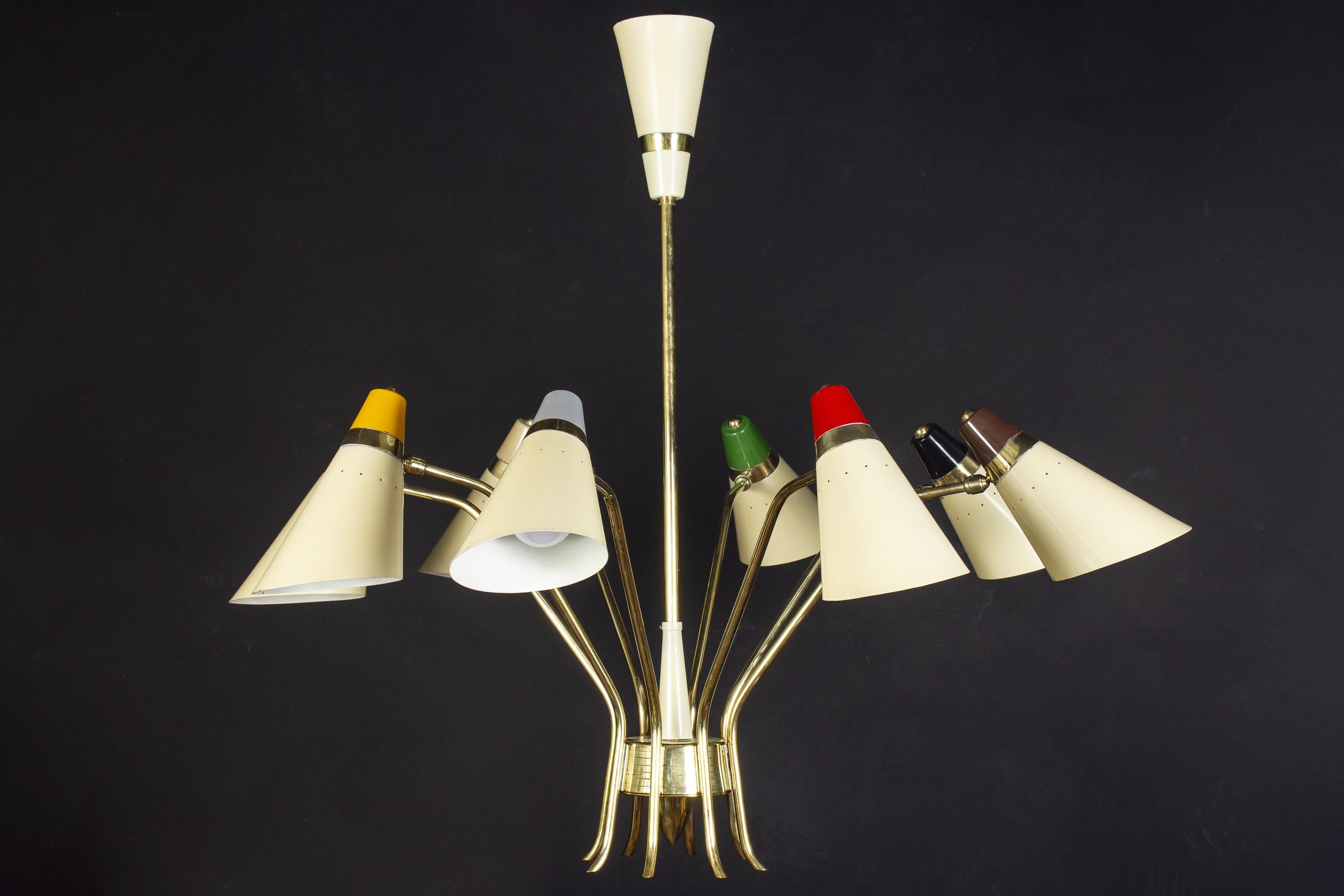 Singular iconic Stilnovo chandelier, features eight rotating arms, each supporting the ivory lacquered and multicolored, perforated shades.
Elegant brass central frame.
This chandelier is in excellent original condition and we can rewire to U.S.