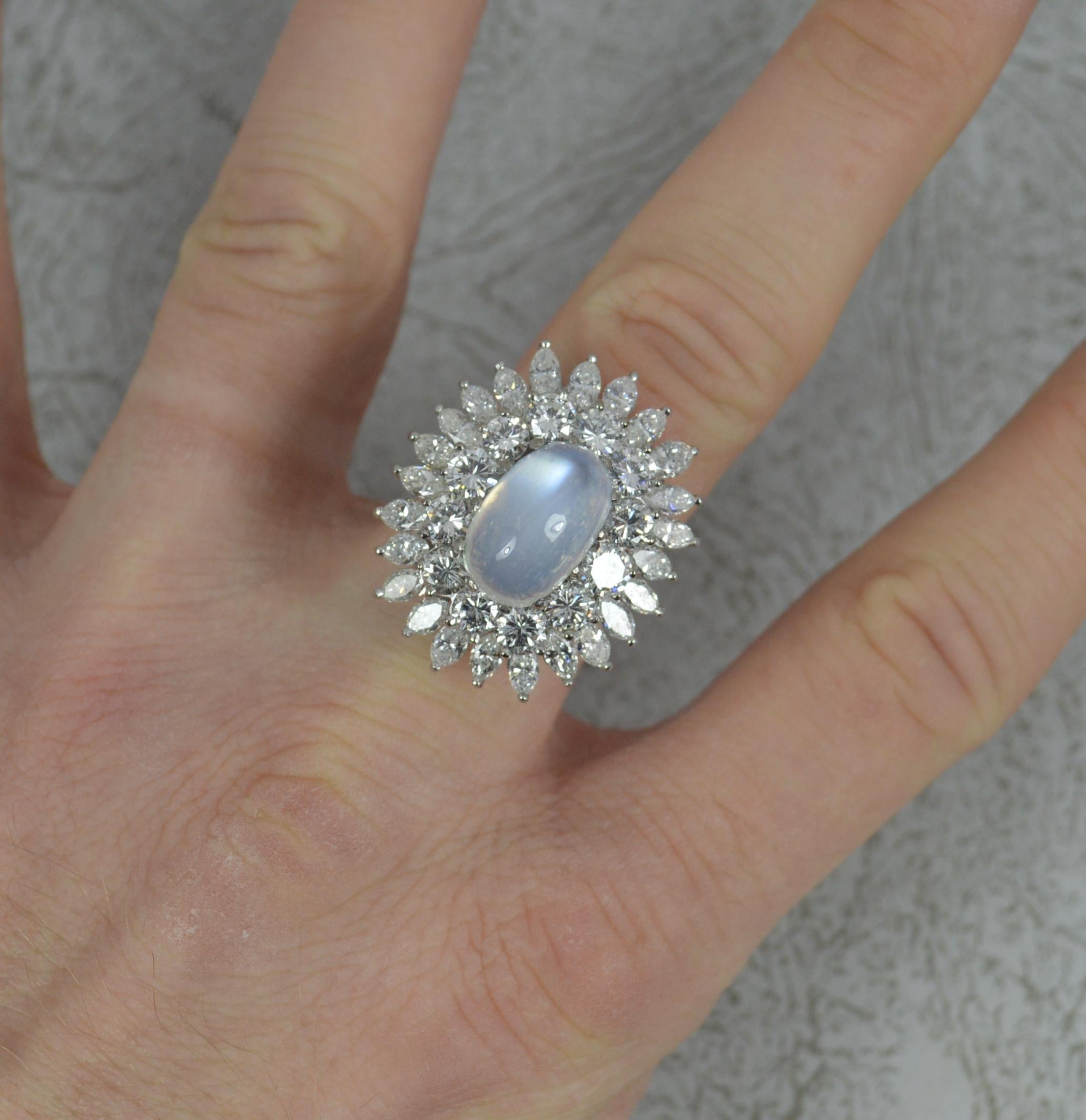 A stunning quality cluster cocktail ring.
Solid 18 carat white gold example.
Designed with an oval shaped moonstone cabochon to centre in multi claw setting. 8mm x 13mm. Full of colour.
Surrounding is a full border of round brilliant cut diamonds