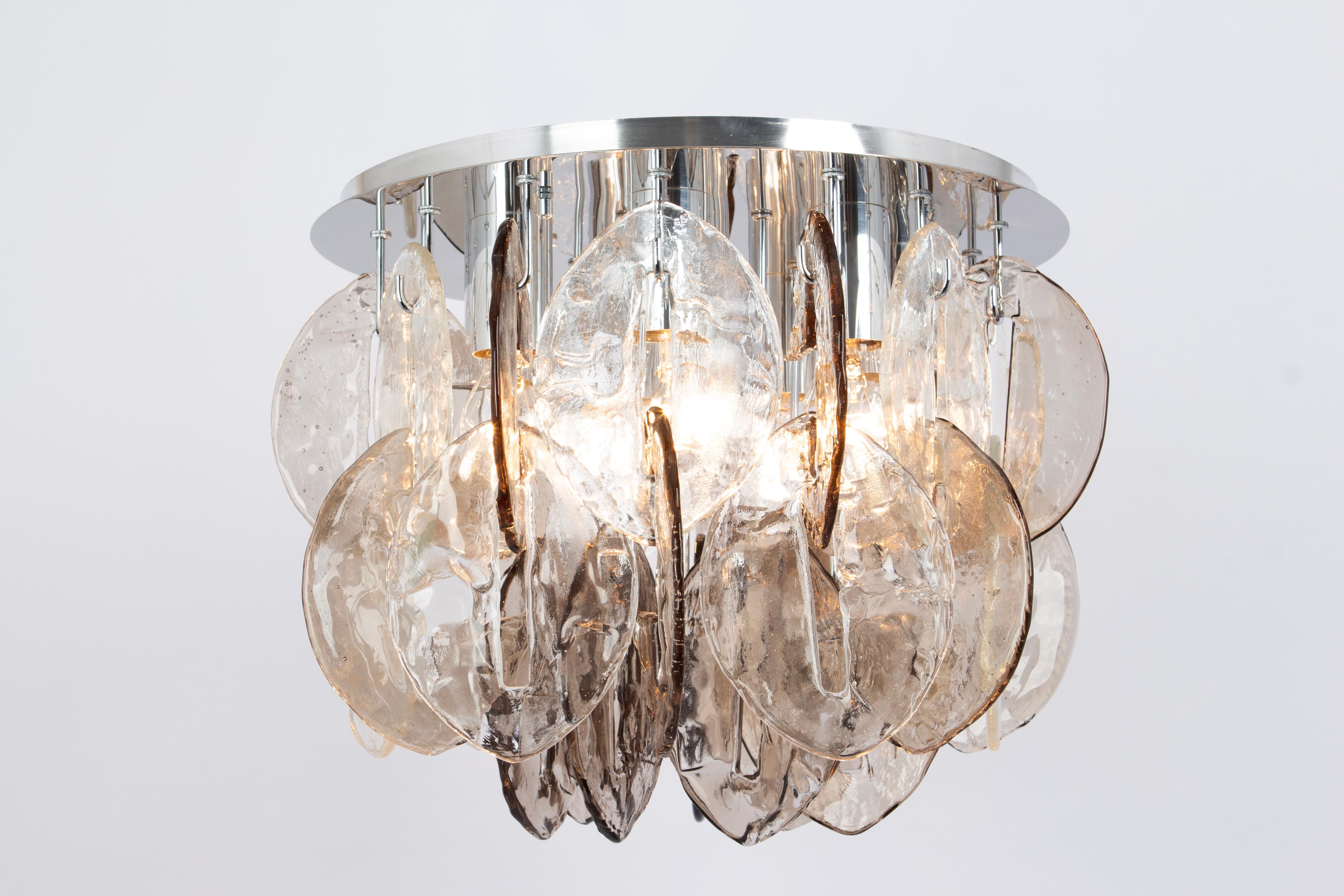 A stunning Large Murano glass Flush mount designed by Carlo Nason for Kalmar, Austria, manufactured in the 1970s. (Serie: CEO)
The Chandelier is composed of 35 thick textured glass elements attached to a chrome metal frame.
Elevate your surroundings