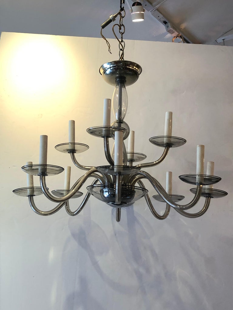 Beautiful simplicity in this Murano glass Italian Mid-Century Modern chandelier having light smoked greyish glass with silver leaf pinstripes on the bobeches. 12 arms, original ceiling canopy and wiring ready to go.