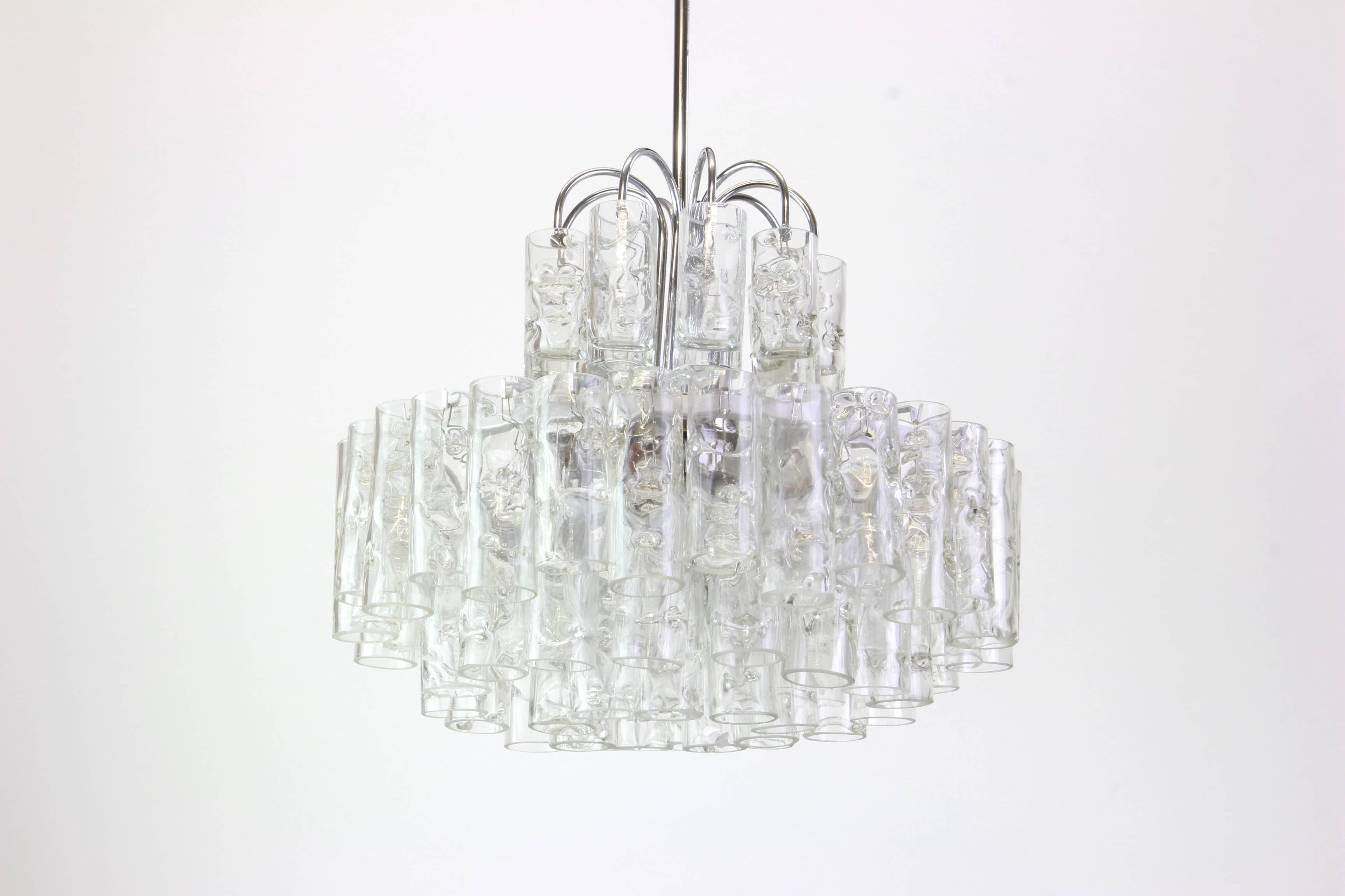 Fantastic four-tier midcentury chandelier by Doria, Germany manufactured, circa 1960-1969. Murano glass cylinders suspended from the fixture.

High quality and in very good condition. Cleaned, well-wired and ready to use. 

The fixture requires 7 x