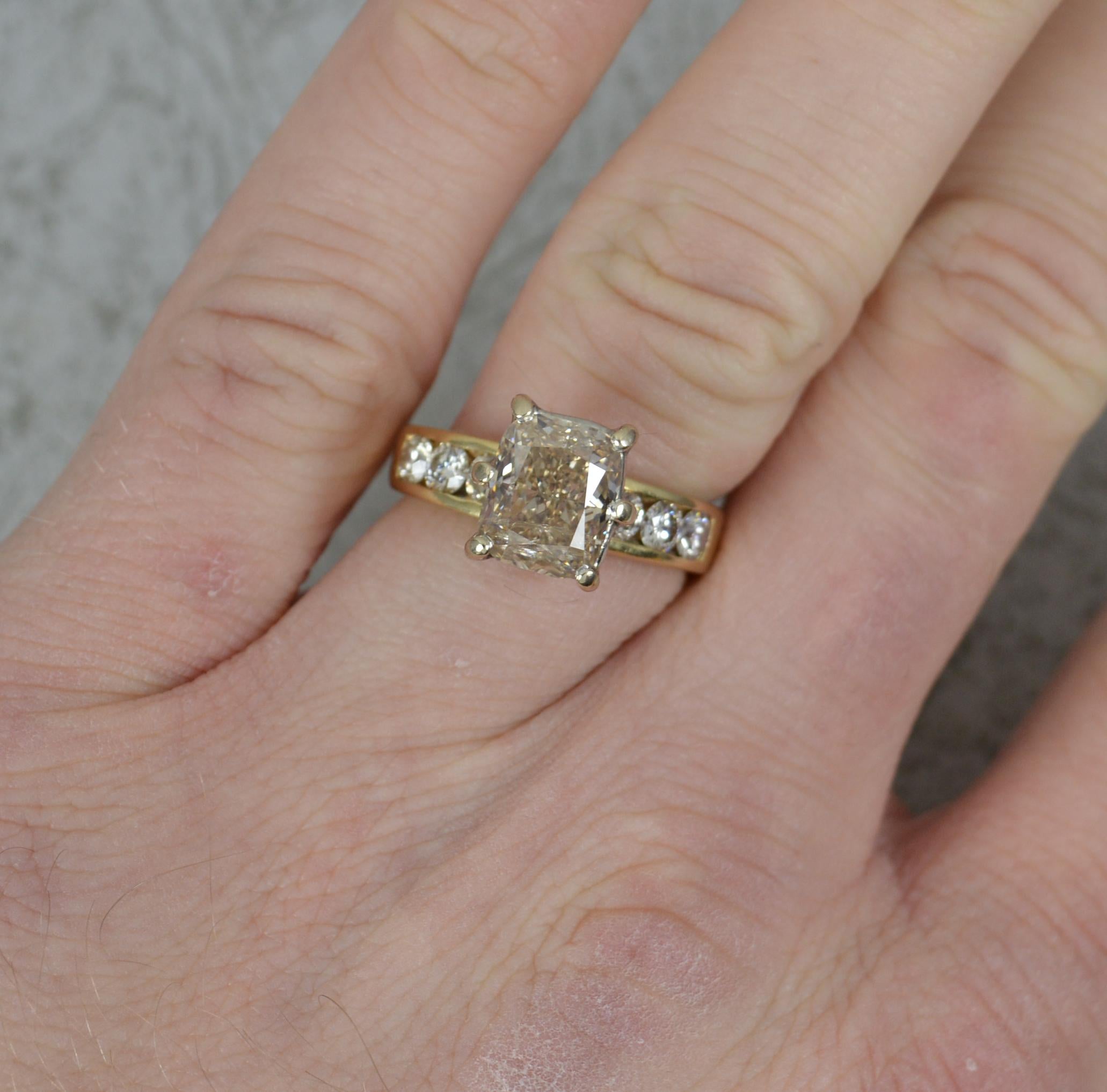 A wonderful diamond engagement ring.
Solid 18 carat yellow gold example.
Designed with a large, radiant cut, natural diamond to centre. 7mm x 8.6mm approx 2.5 carats approx. To the shoulders are an additional six round brilliant cut diamonds,