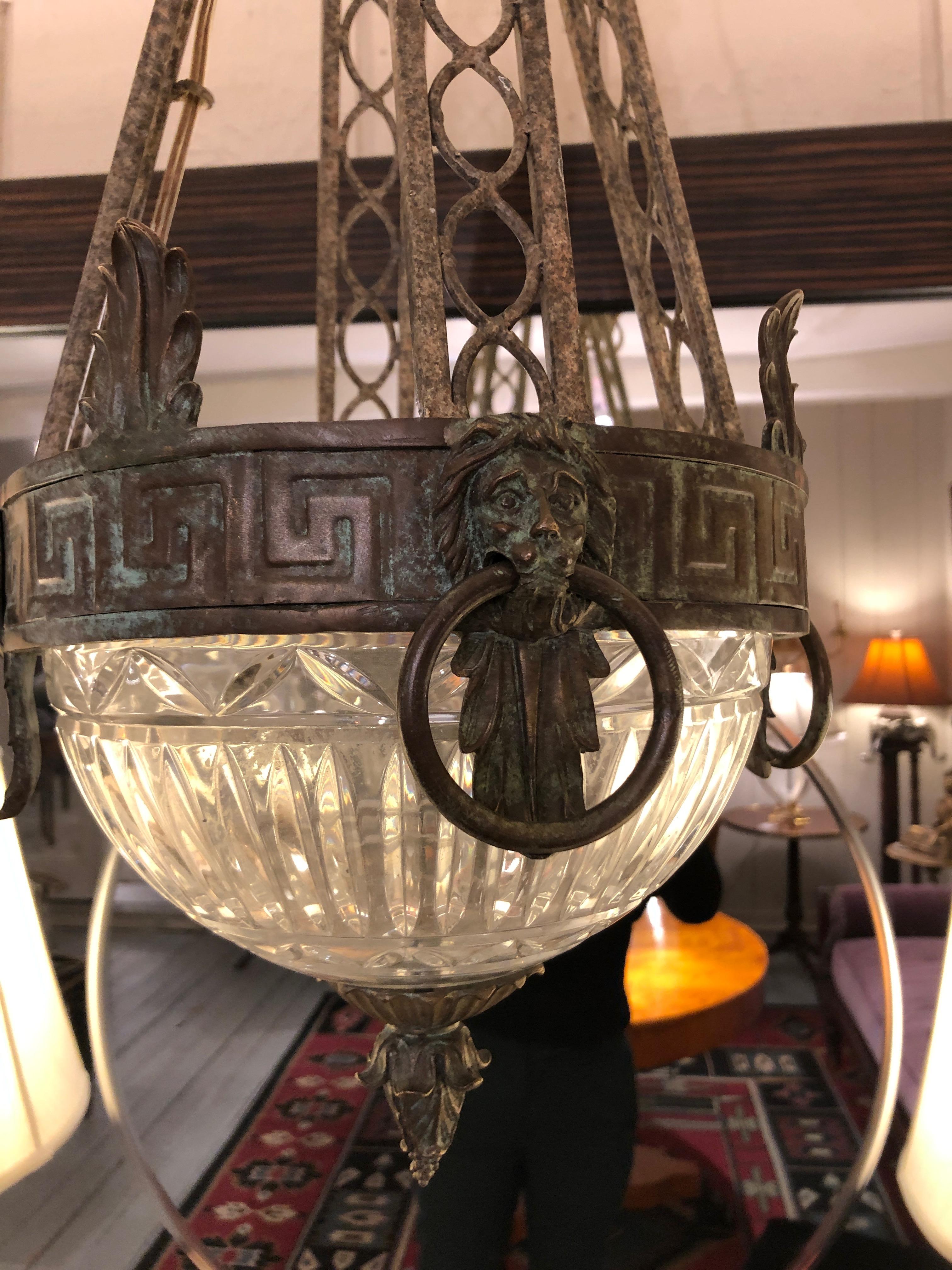 A stunning chandelier having a dome shaped cut glass bottom with handsome neoclassical iron top band of Greek keys and lions and triangular shaped arms that meet at the apex.
CT.