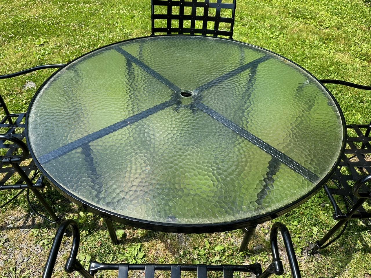 Juego de exterior de aluminio de alta gama Brown Jordan con mesa redonda con tapa de cristal y 4 bonitos sillones con asientos y respaldos de aluminio tejido con tachuelas decorativas.  Decapado profesional, pintado de negro y recubierto de