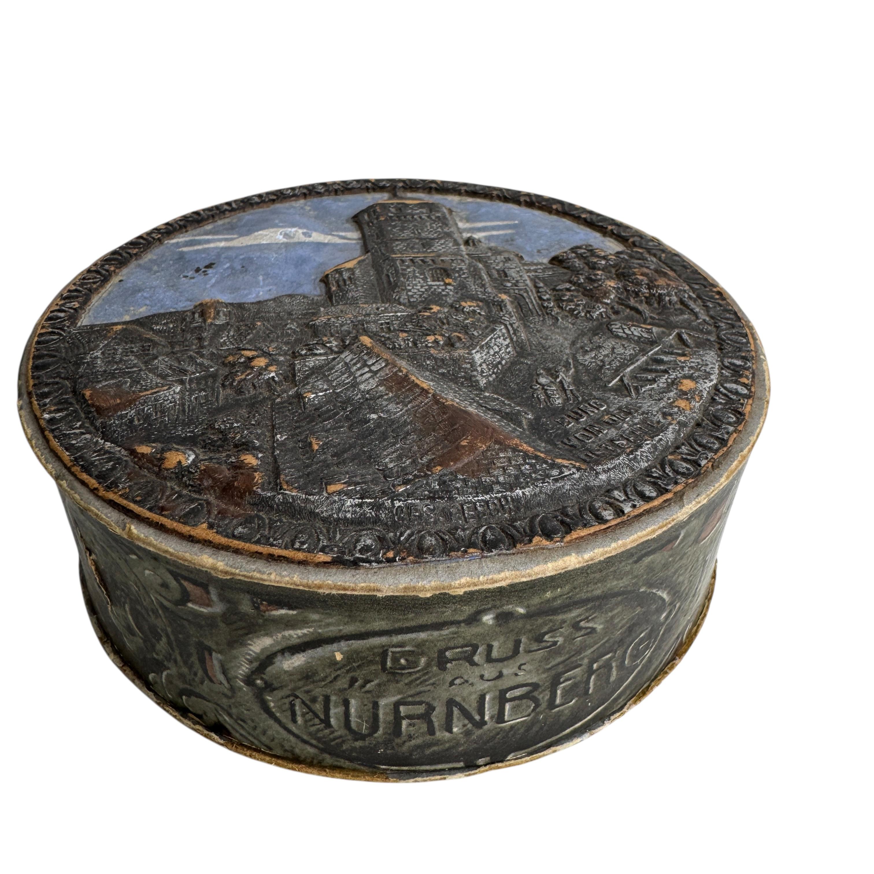 Étonnante et rare boîte de forme ronde, fabriquée à la main en carton et datant des années 1910 ou plus anciennes. La partie supérieure de la boîte montre une vue du château de Nuremberg en optique 3D.
Cette boîte antique est d'origine allemande,