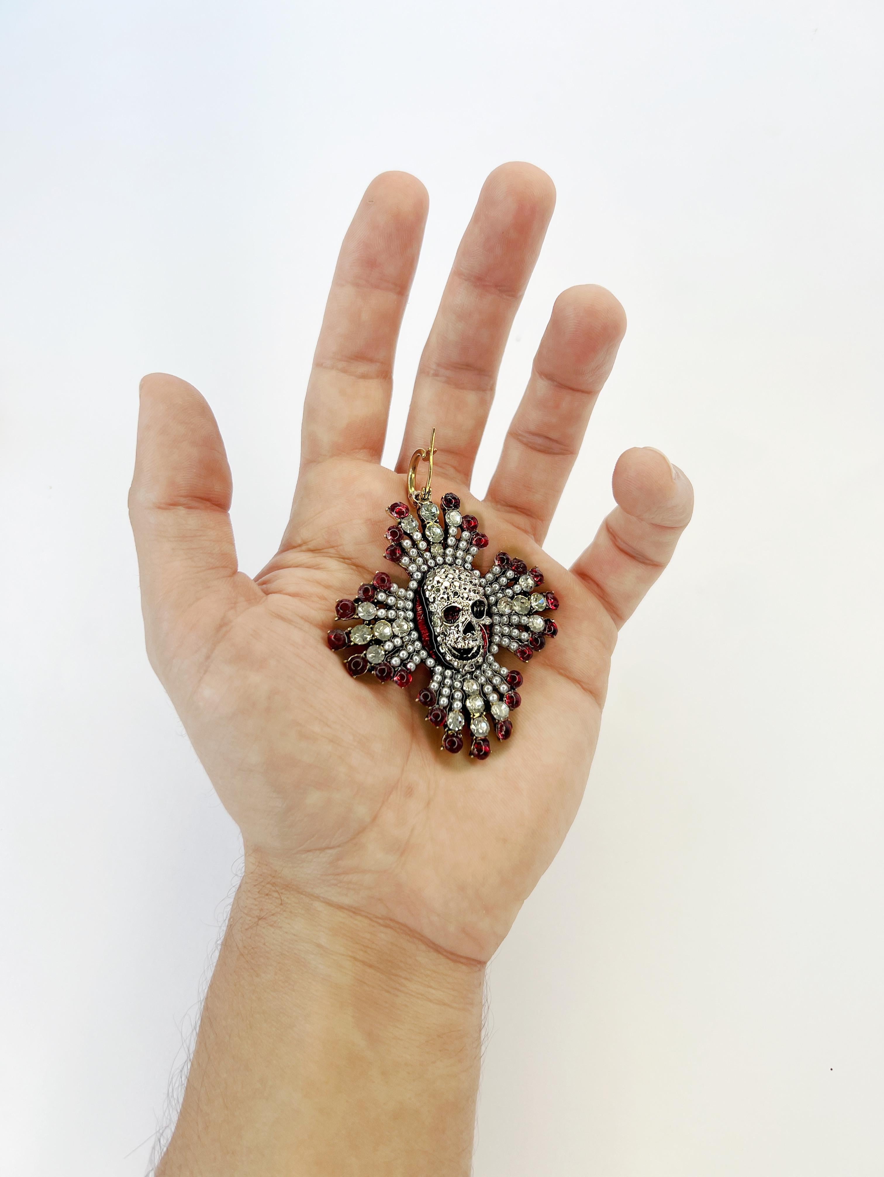 Make a bold statement with these one-of-a-kind earrings, featuring a daring white gold plated skull at the center. Drenched in Swarovski crystals and accented with lustrous pearls, these earrings exude eccentric elegance. Their unique design blends