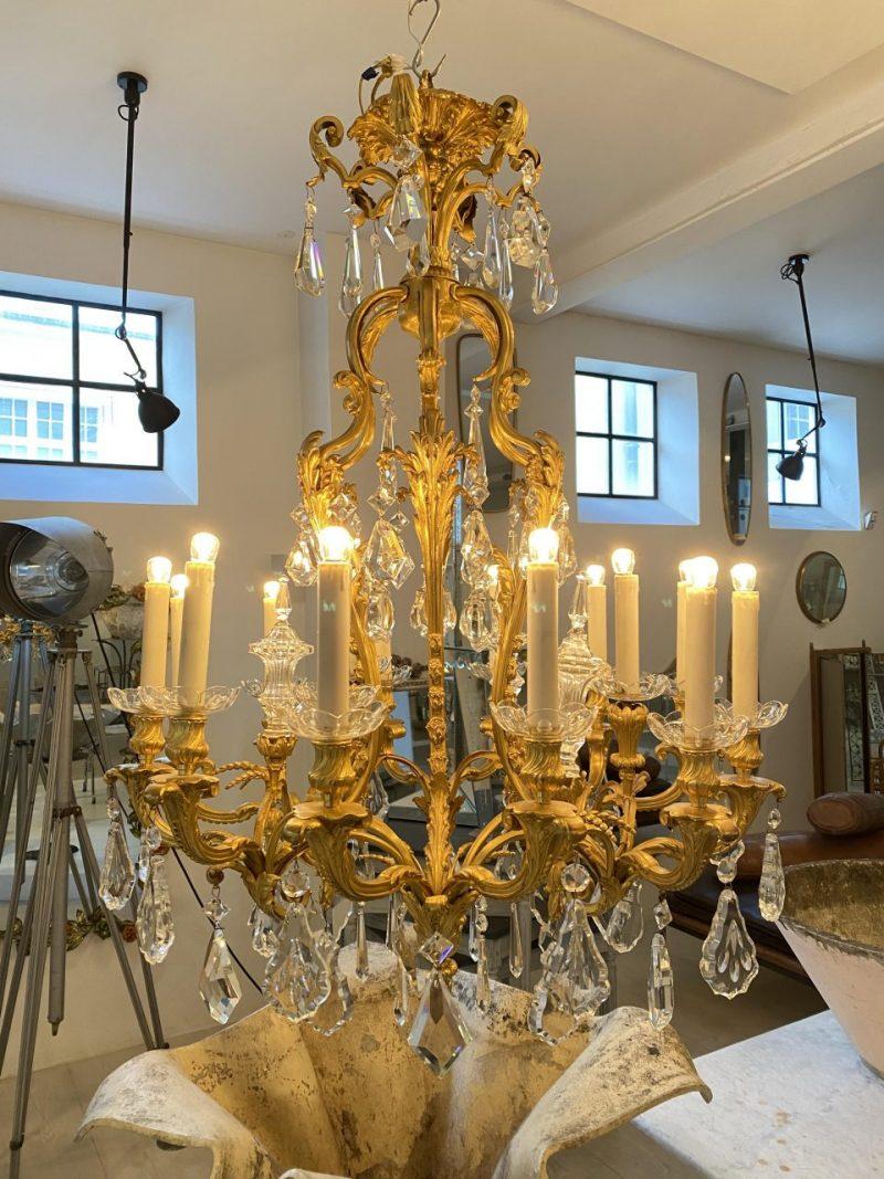 Large and handsome chandelier in an opulent gilded bronze frame, from France around the 1890s, with rococo style elegant faceted prisms and 3 glass spires.

Wonderfully beautifully decorated with countless curved acanthus leaves and has 15 light