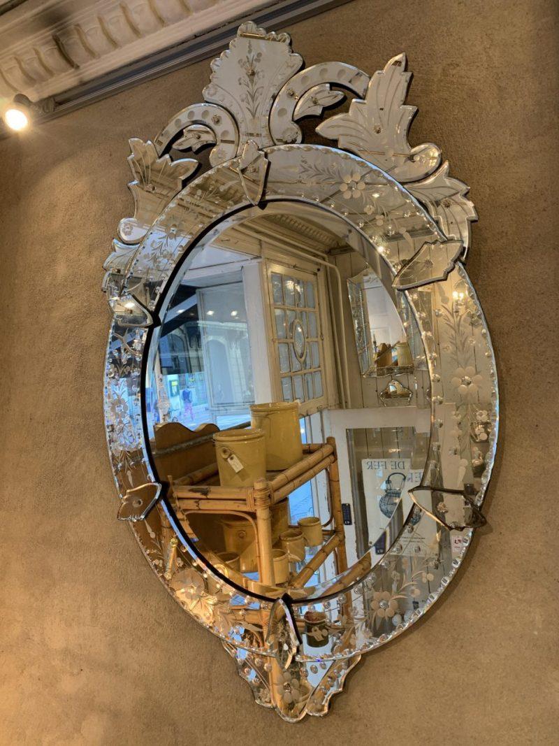 Lovely mirrored wall mirror in Venetian style, in a stunningly beautiful ornate oval design. Circa 1920s-40s France. Original faceted mirror glass still preserved.

Note the beautiful floral ornamentation in the divided mirror frame along the edge