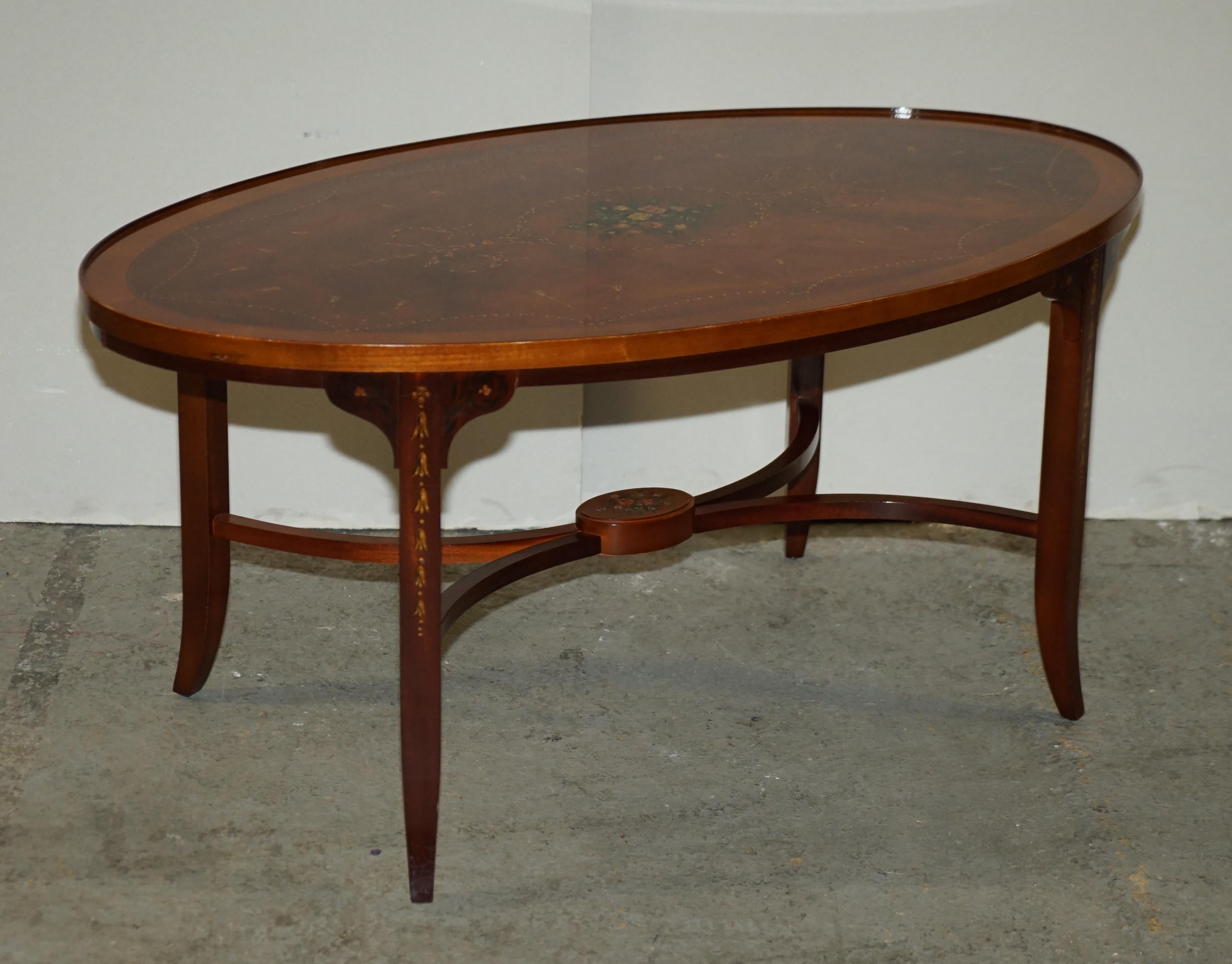 Here we have for sale a lovely oval mahogany and inlaid coffee table with splayed legs united by stretchers.

This table is hand-painted in a stunning floral design with Sheraton-style detailing.

Overall, the table is in good condition it has
