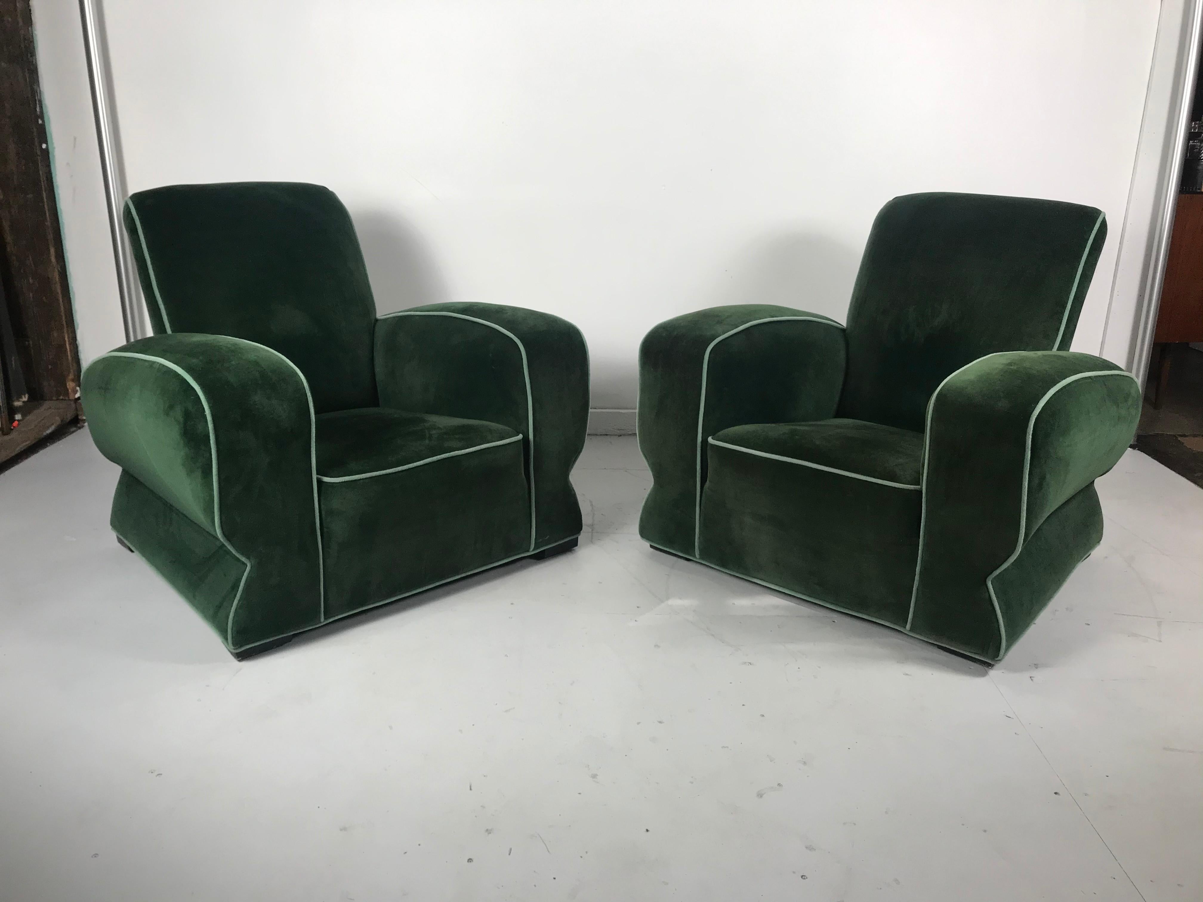 Stunning pair of Art Deco club. Lounge chairs, streamline modernist design 1930s, recently reupholstered in emerald green velvet with ice blue piping. Look amazing from any angle. Extremely comfortable, would fit seamlessly into any modern,
