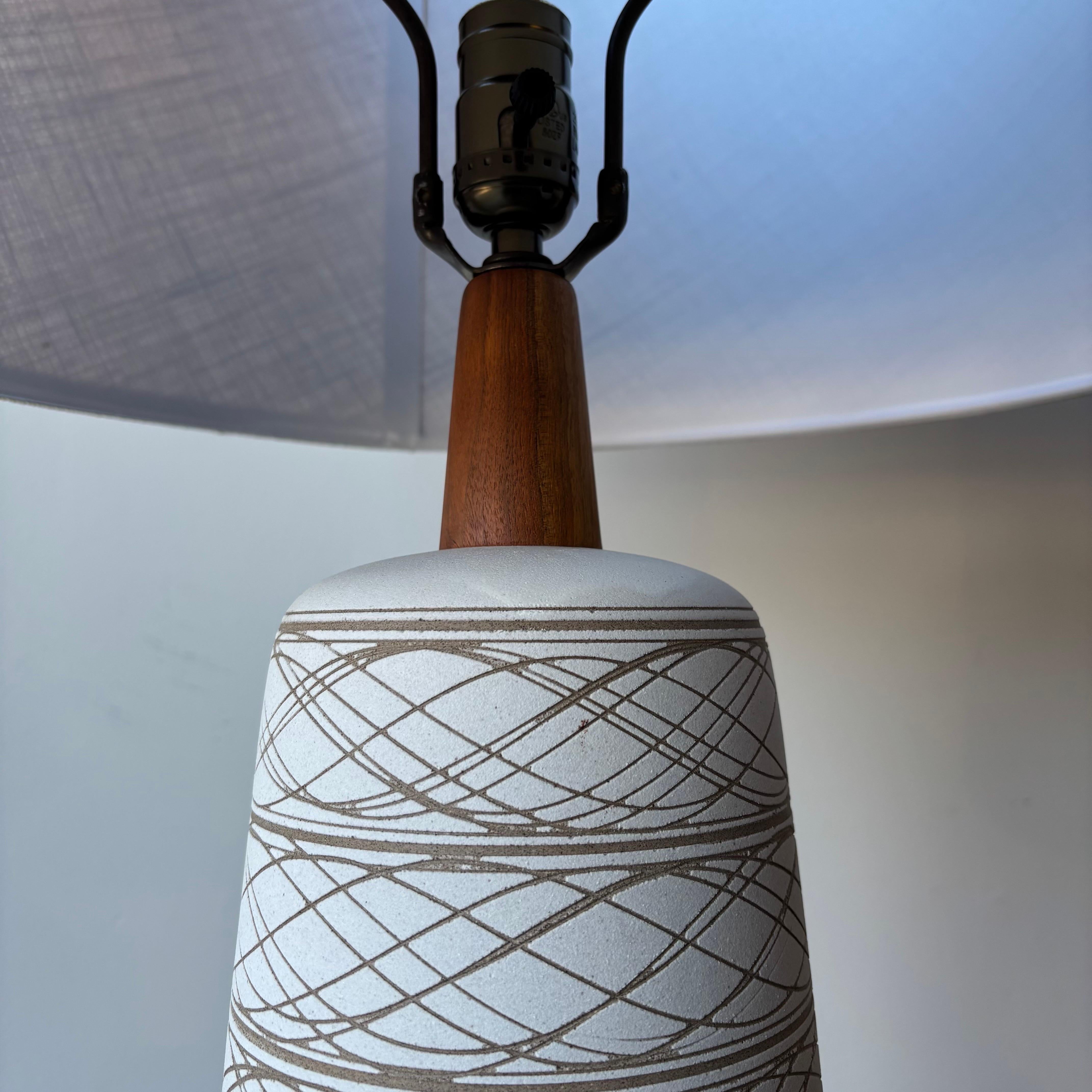 Une superbe paire vintage moderne des studios Marshall, Jane et Gordon Martz. Céramique ivoire avec accents de noyer et fleurons d'origine.  Nouveaux abat-jour en toile de jute.
L'un d'eux conserve l'autocollant d'origine.
