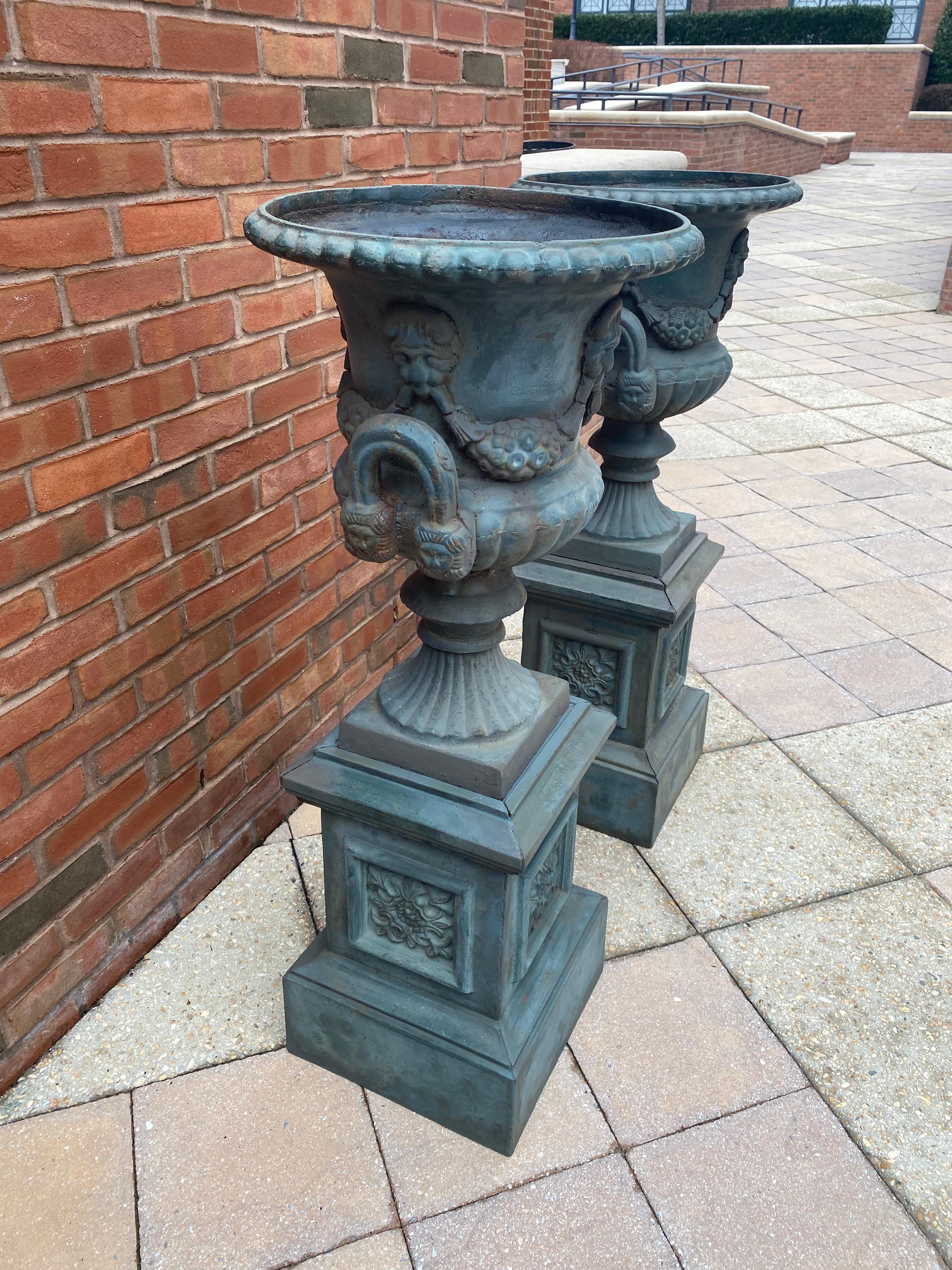Impressive pair of 19th century cast iron garden urns.  Urns have amazing verdigris coloring and patina. 
Adorned with medallions and fruit, sitting on equally impressive pedestal bases.  
Recently refreshed by professional restorer. 

4 pieces- 2