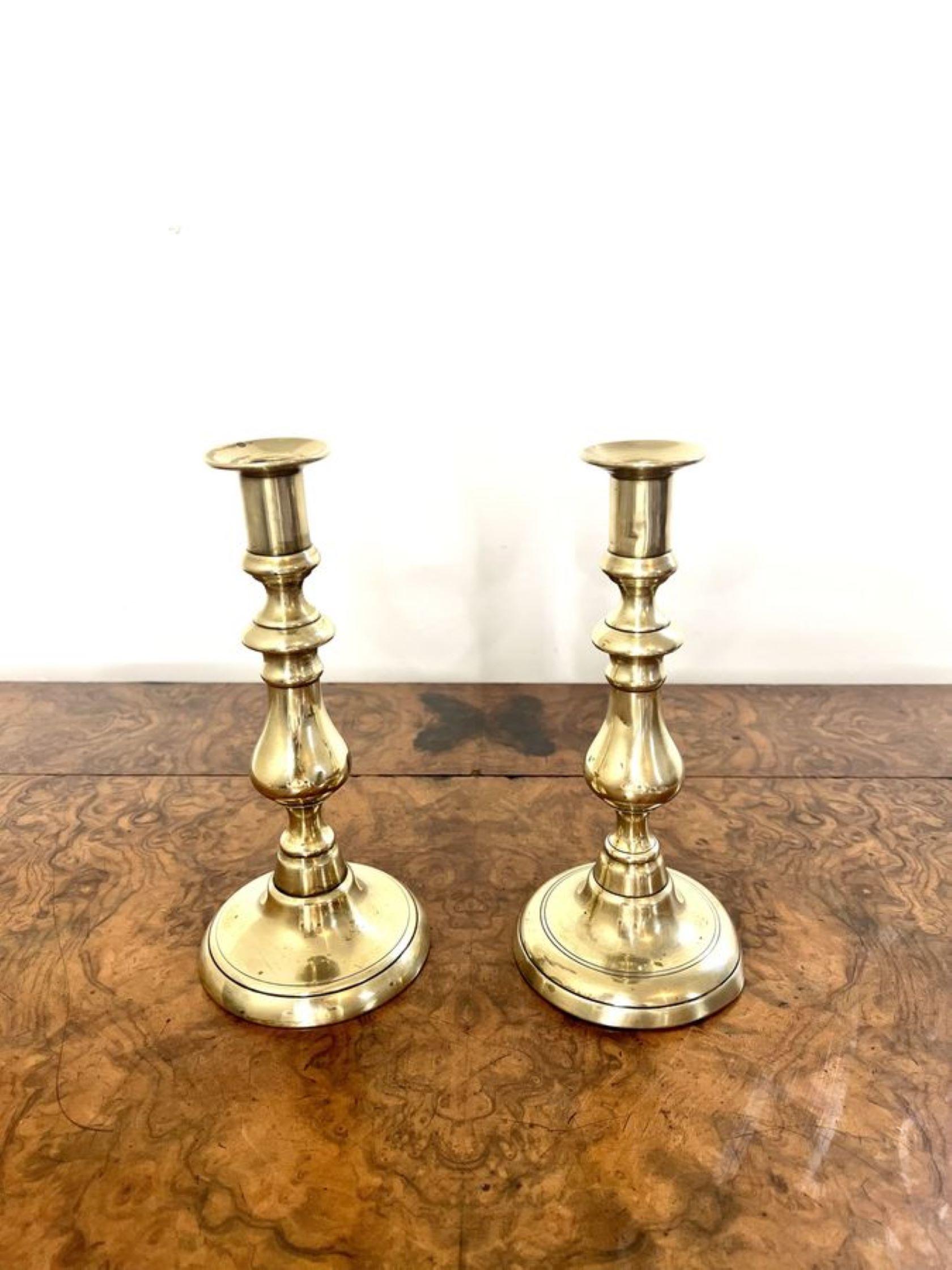 Superbe paire de chandeliers anciens en laiton de l'époque victorienne ayant une élégante paire de chandeliers en laiton élevés sur des bases circulaires. 

D. 1880