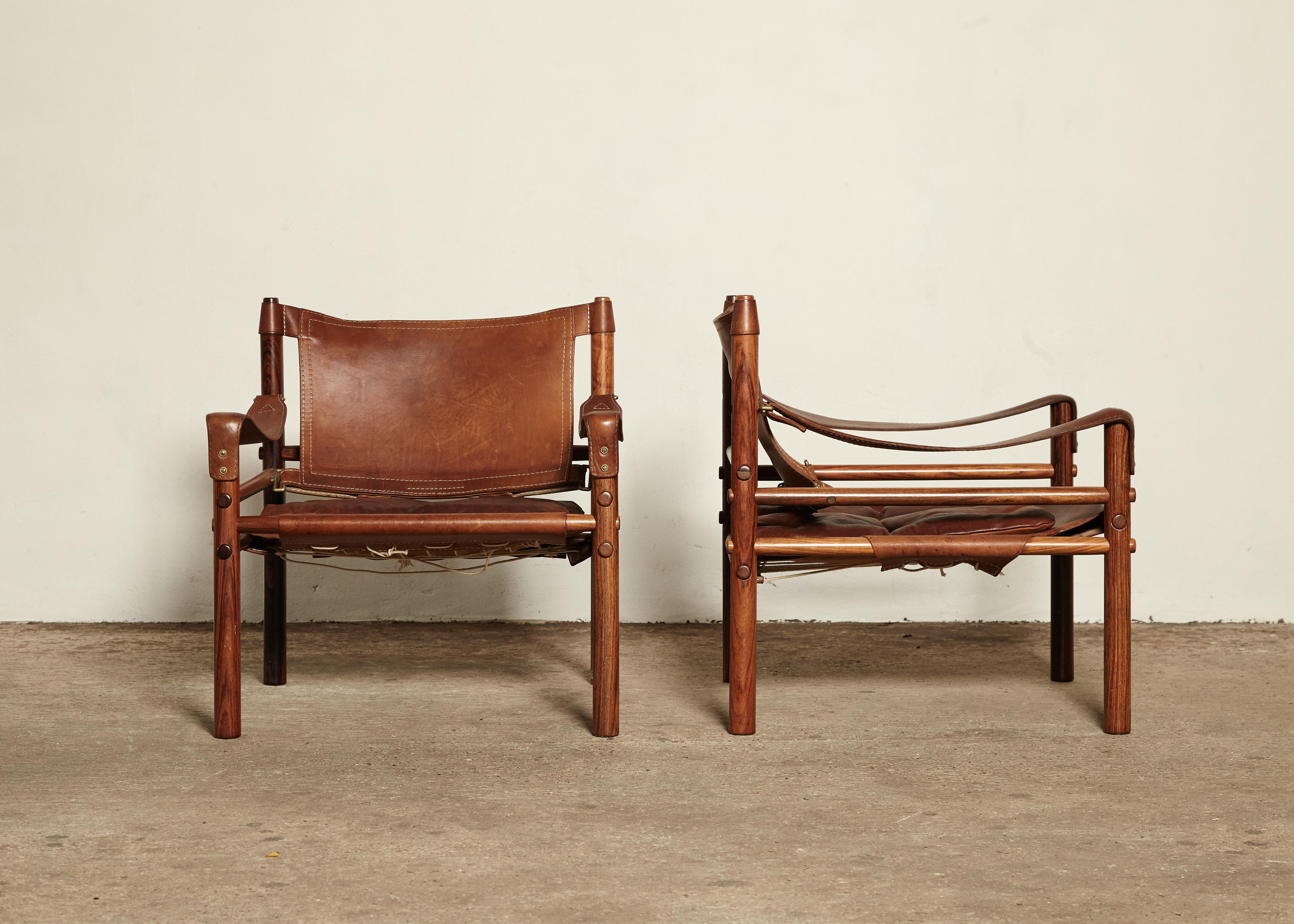 A stunning pair of authentic vintage Arne Norell safari sirocco chairs in rosewood and beautifully patinated brown leather. Made by Norell Mobler in Sweden. Wonderful original condition and rarely found with such special wood grain and patinated