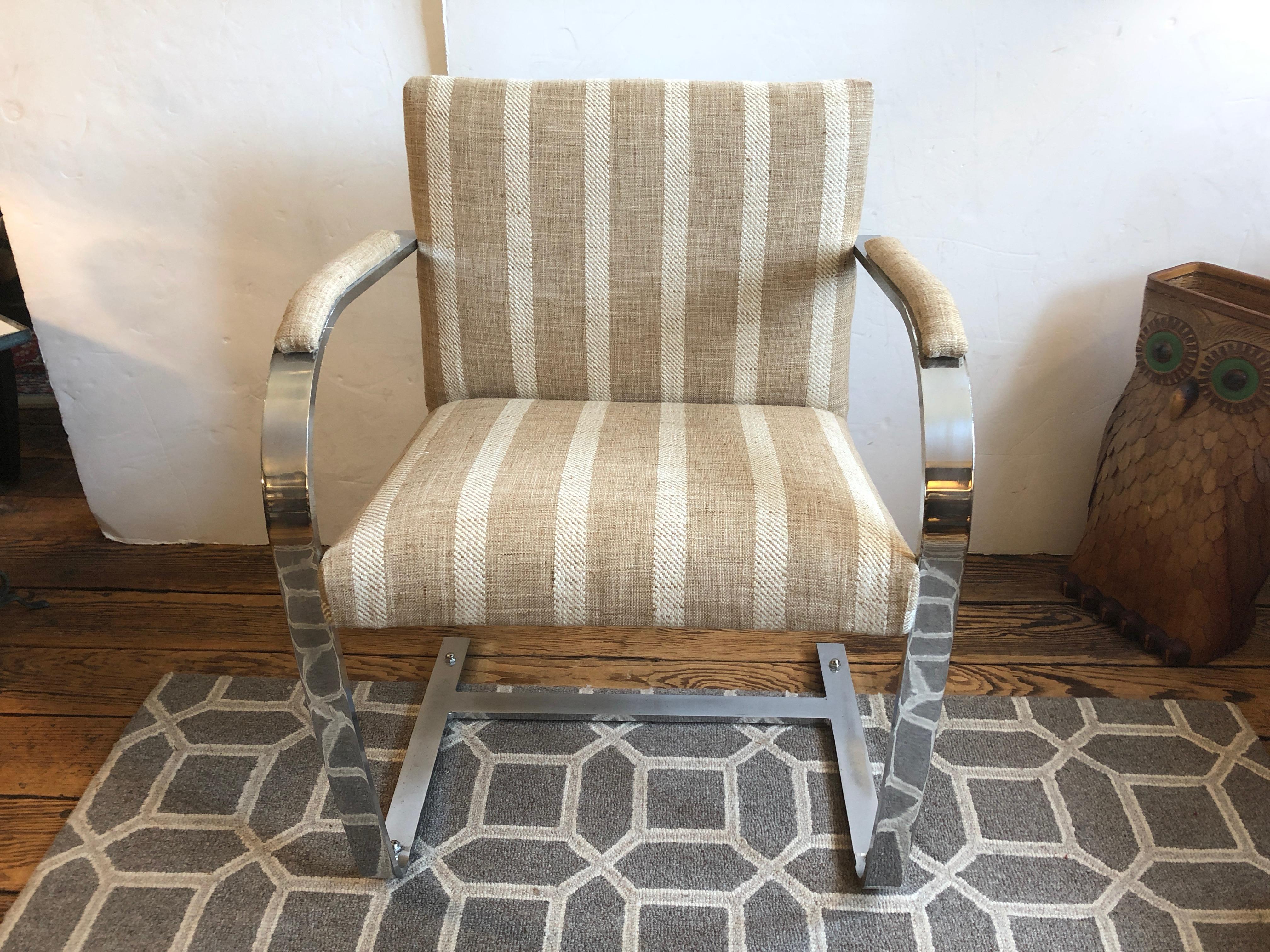 Handsome pair of Mid-Century Modern armchairs in the style of Milo Baughman having heavy chrome curved arms and base, recently upholstered in a neutral chic nubby striped tan and white striped fabric.
