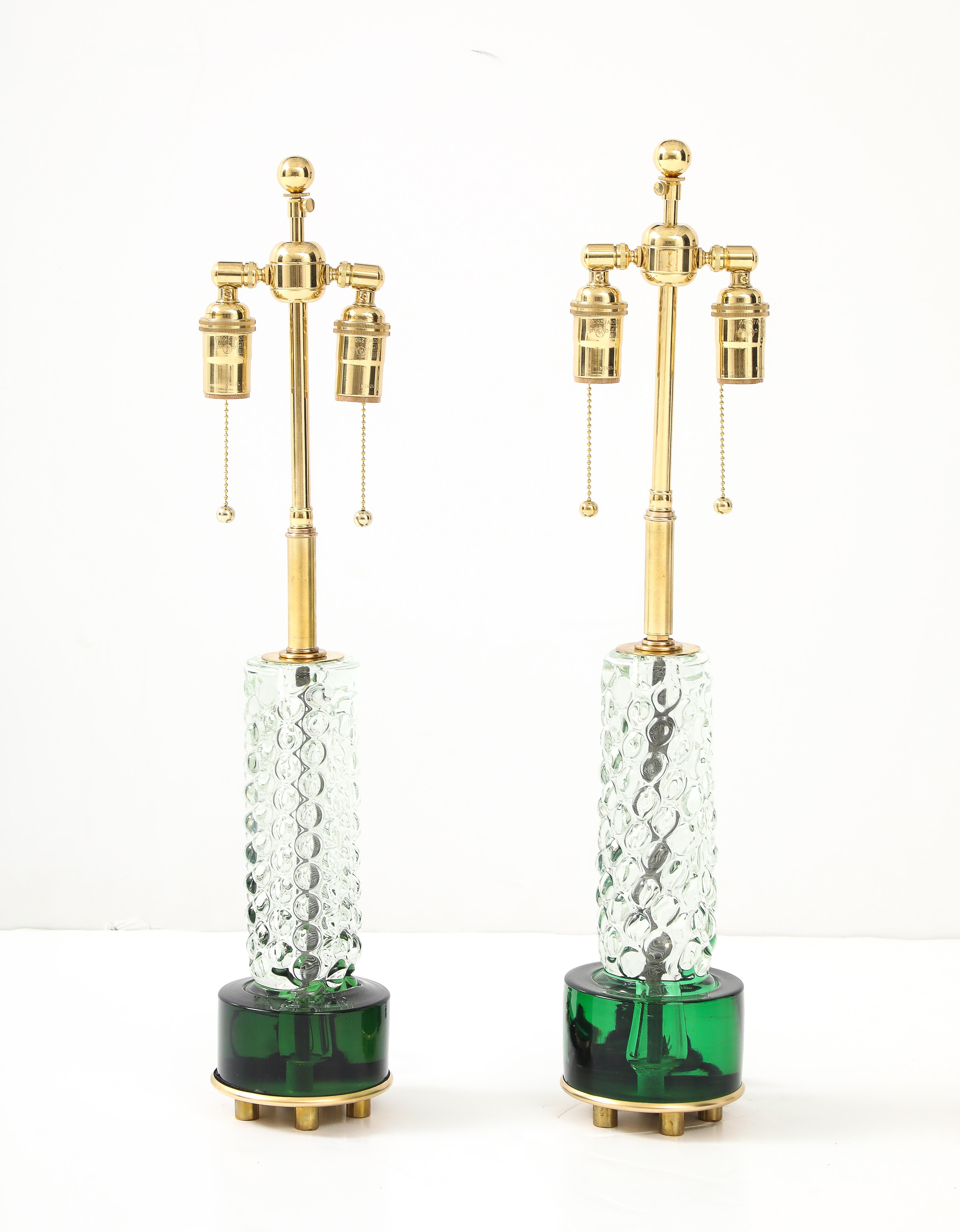 Paire de lampes en cristal clair et émeraude des années 1950.
L'épaisse base de couleur émeraude intense incorporée aux bulles de cristal clair forme une paire de lampes étonnante. 
Elles ont été nouvellement câblées avec des doubles grappes