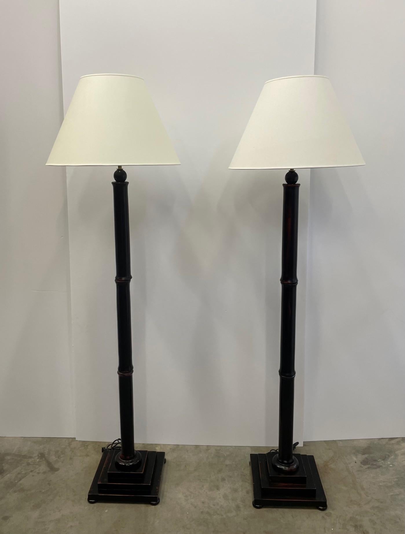 A matching pair of vintage faux bamboo floor lamps having a handsome black rubbed finish. 
Shades not included. Top of socket 62; top of harp 73.