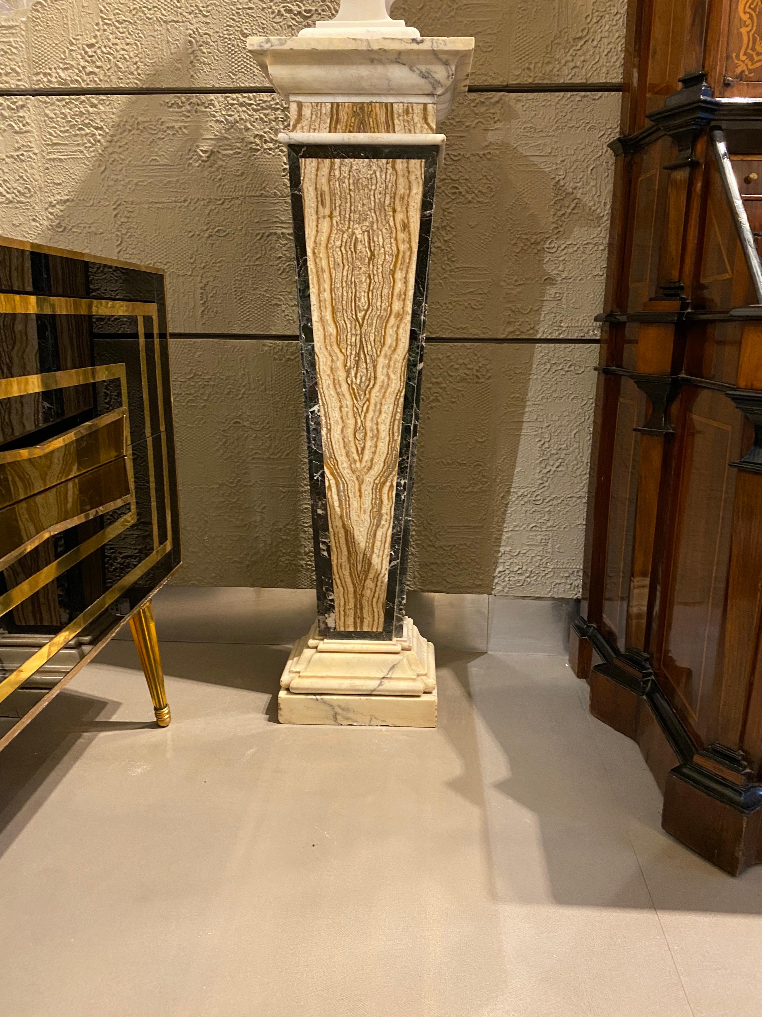 Cette élégante paire de piédestaux effilés est surélevée par des  socles rectangulaires en marbre blanc de Carrare à bords marbrés. La colonne fuselée aux angles coupés présente un 