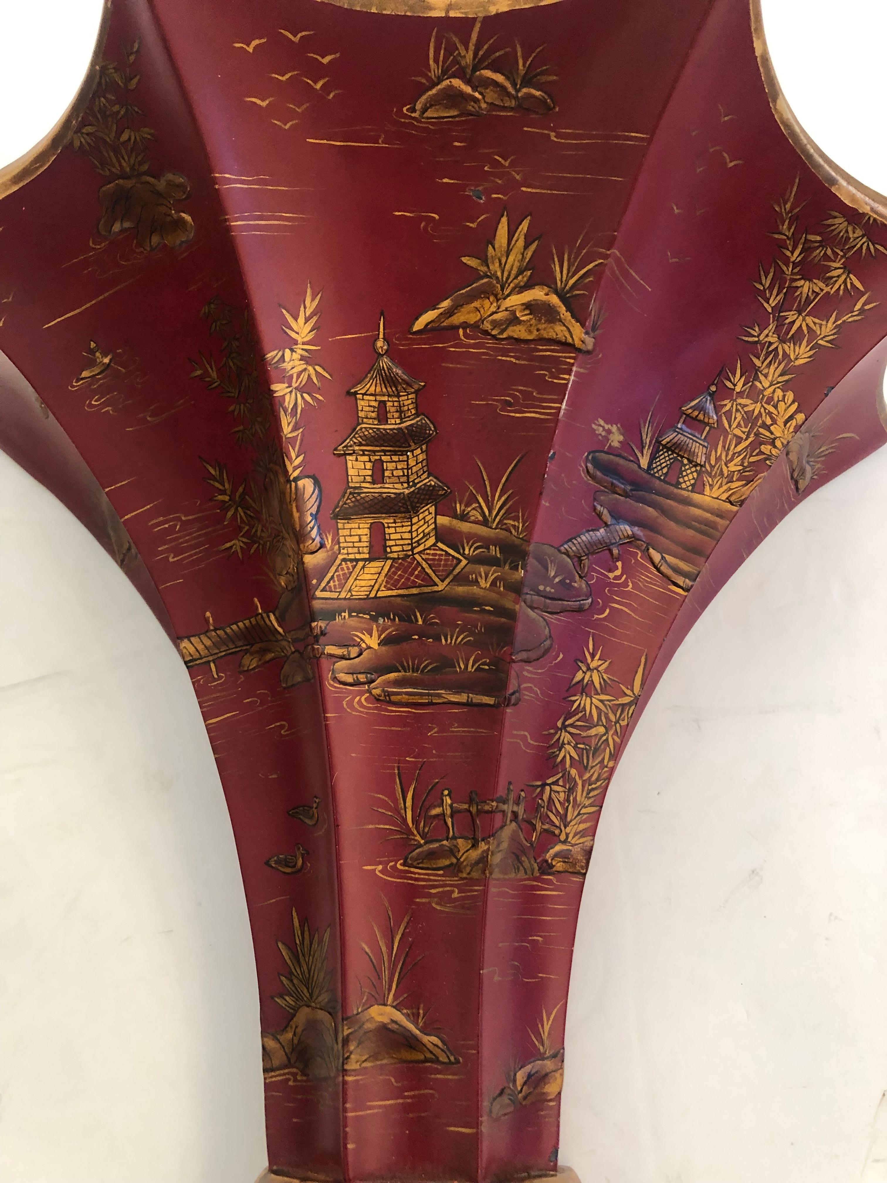 Large decorative pair of chinoiserie fluted wall brackets or sconces in a marvelous shade of red having black figural painting and gold flourishes. The interiors are hollow so could contain dried flowers or such.