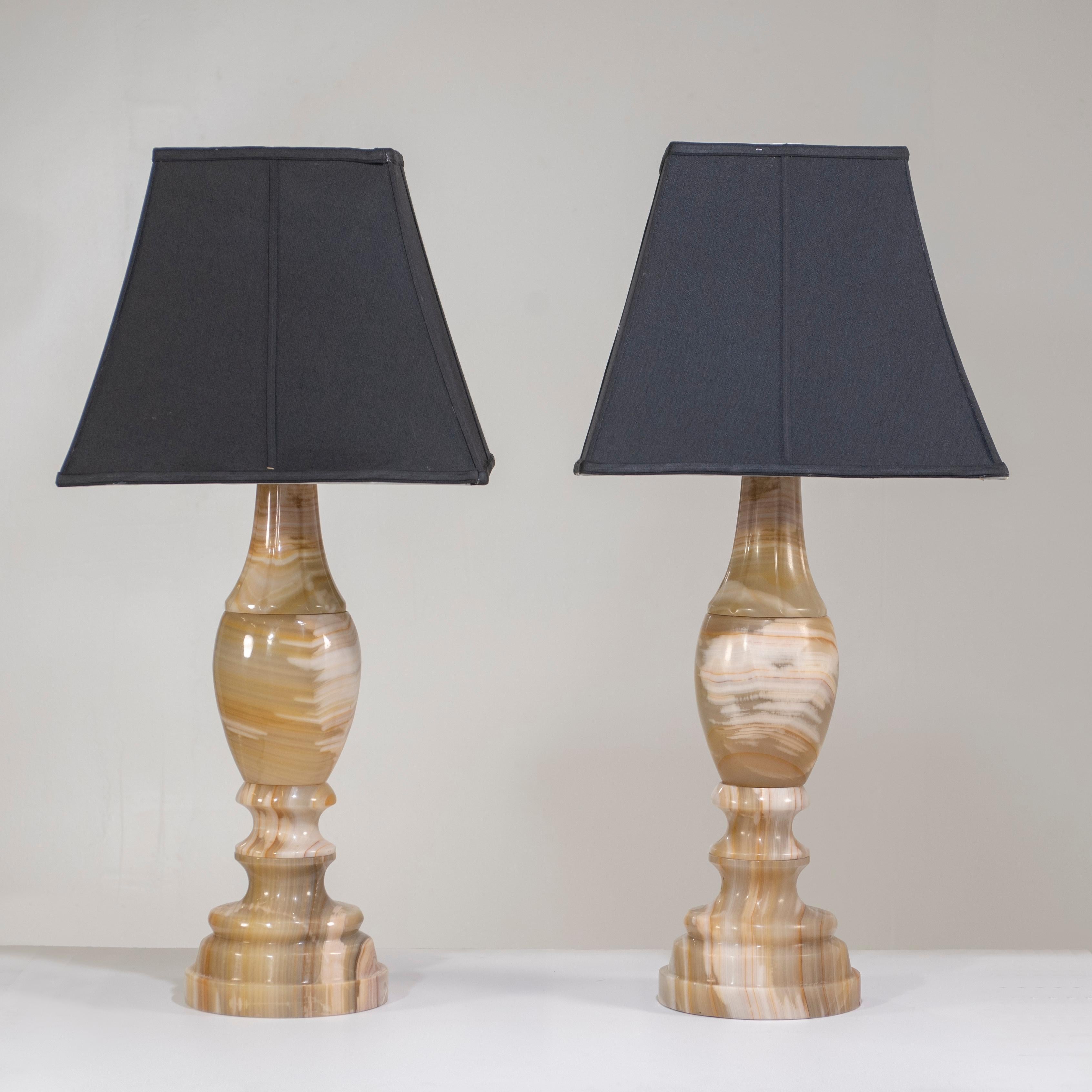 A pair of impressively large scale onyx table lamps with gorgeous coloration and heft. The lampshades and harps are not included.