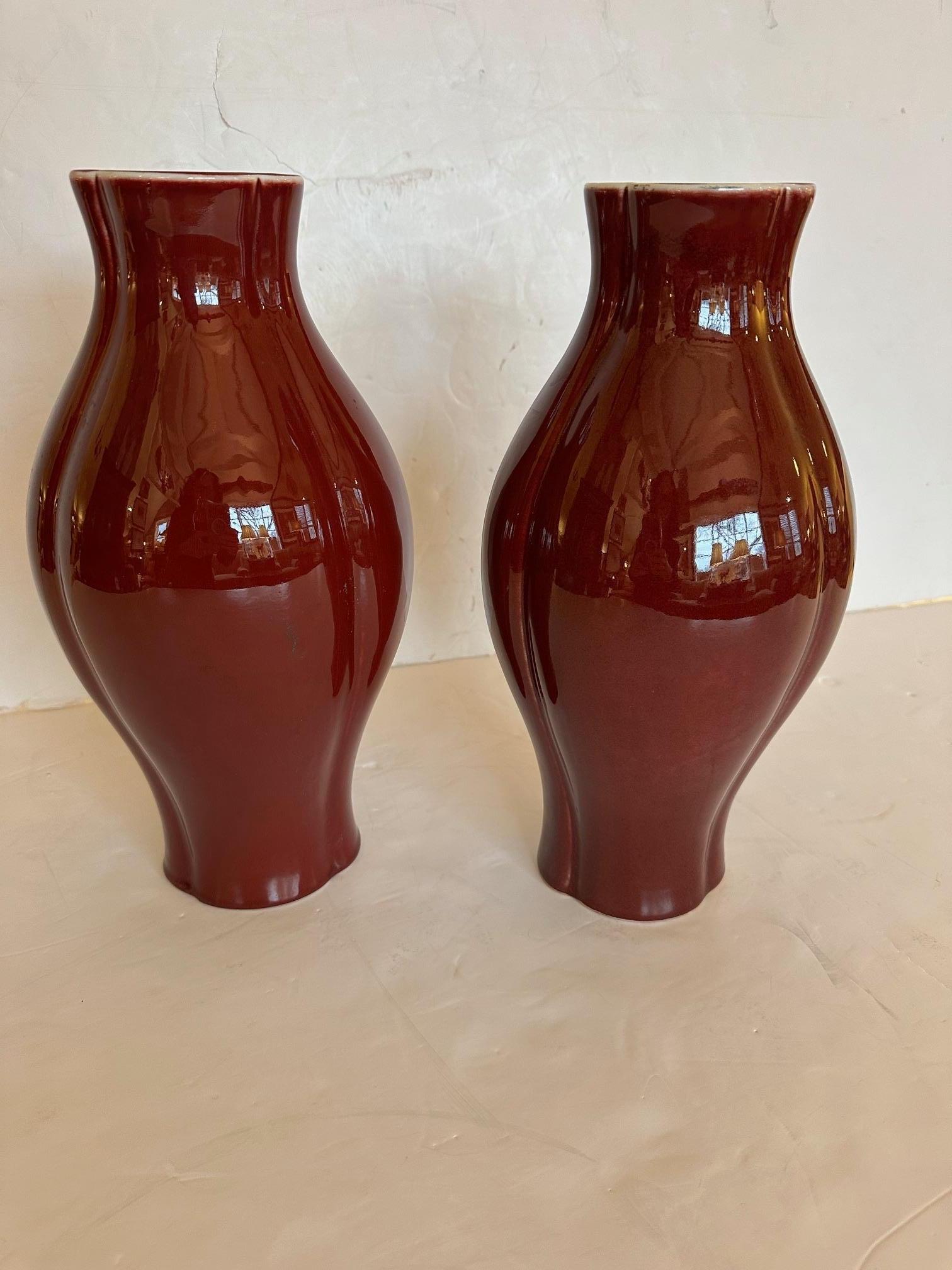 Jolie paire de vases en céramique de couleur sang de bœuf, à la glaçure brillante, dont le haut et le bas sont joliment festonnés.