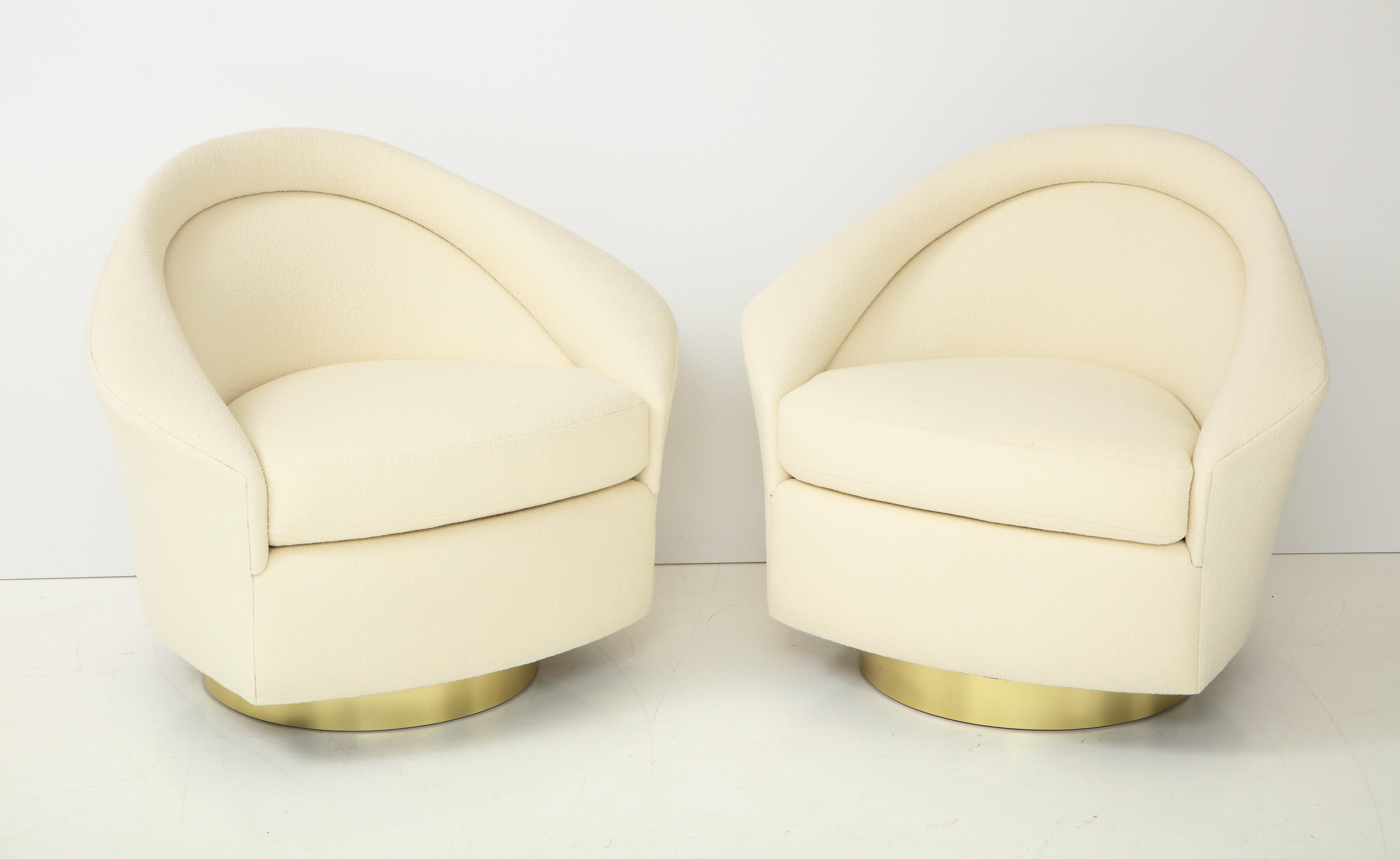 Stunning pair of Milo Baughman swivel chairs.
The chairs have elegant lines with detailed arms, and they have been newly reupholstered in a beautiful Ivory Knoll bouclé fabric.
They are mounted on polished brass trim swivel bases.