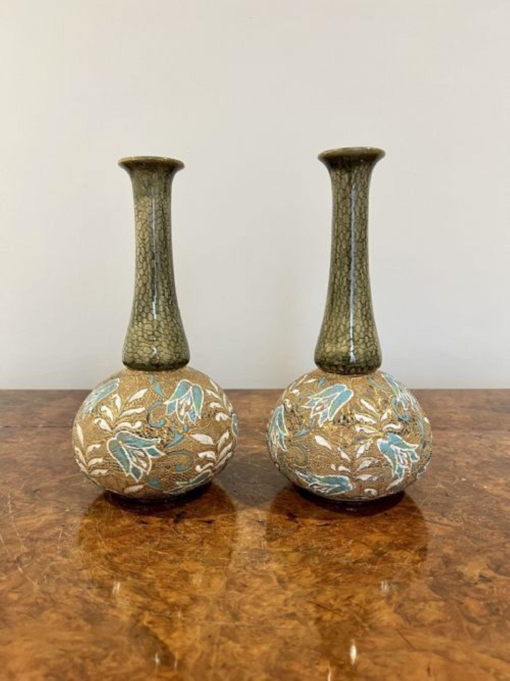 Une paire de vases Doulton de qualité, de forme ancienne, ayant un corps de forme bulbeuse avec des tubes en relief en blanc, bleu et or décorés de fleurs et de feuilles avec des sommets en forme de vert. 