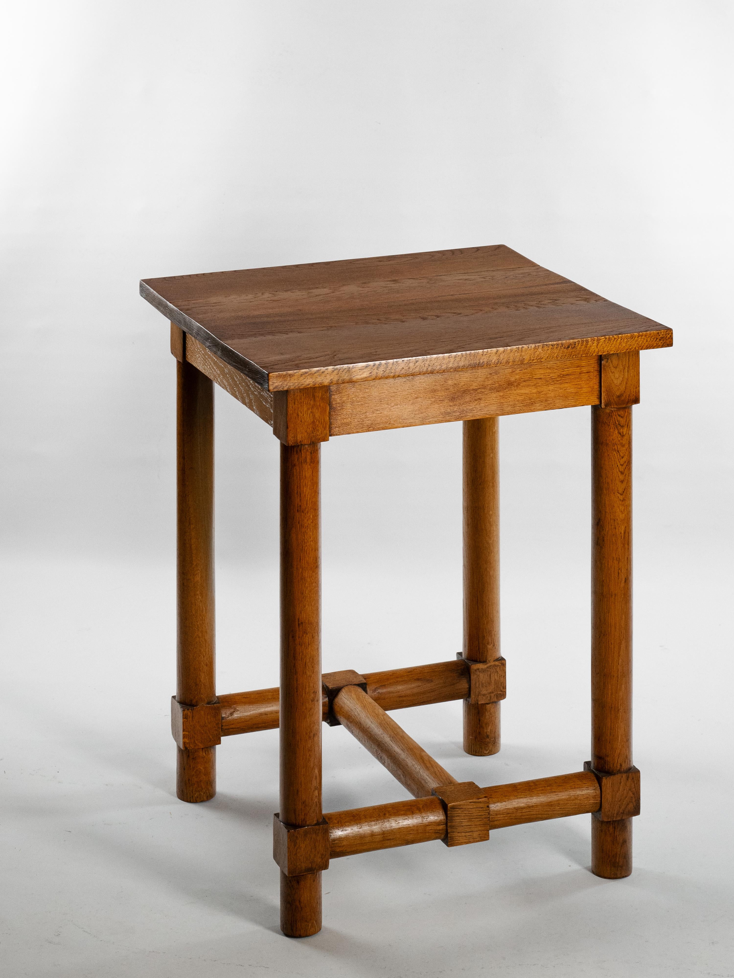 This pair of side tables, crafted from solid oak (or tropical wood?), epitomizes Jacques Adnet's refined, functional design philosophy from the 1940s. Each table boasts clean, geometric lines, a square top, and sturdy legs reinforced by crossbars.