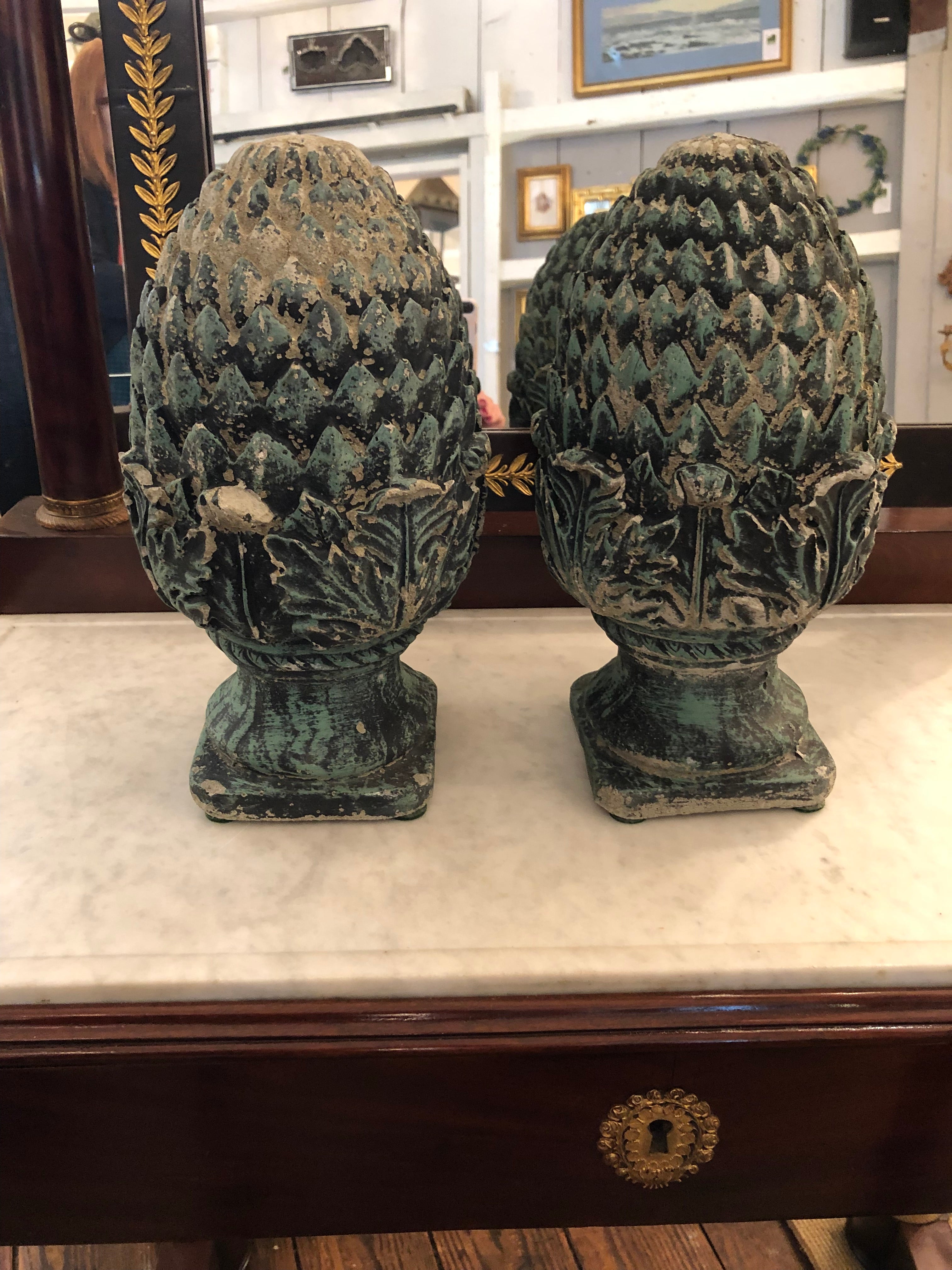 Timeless pineapple motife cast cement finials or acorns having marvelous aged and verdigris patina. The imperfections where some of the cement has chipped off, and the slight differences in the finials, adds to the beauty. Can be used in the garden