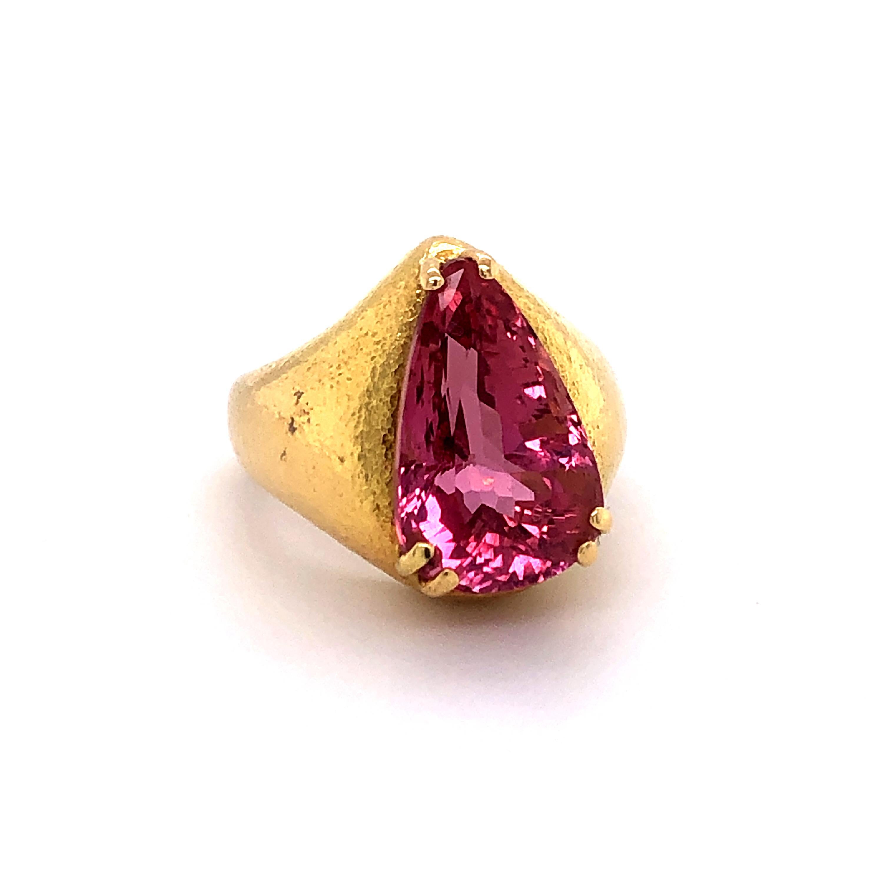 This beautifully handcrafted and hammered ring in 18 karat yellow gold features an intensely colored pear shaped pink topaz. The superbly cut topaz weighs approximately 8.00 carats.

SIze: 51 (EU), 5 3/4 (US)
Maker's mark: JUD
Assay mark: 750