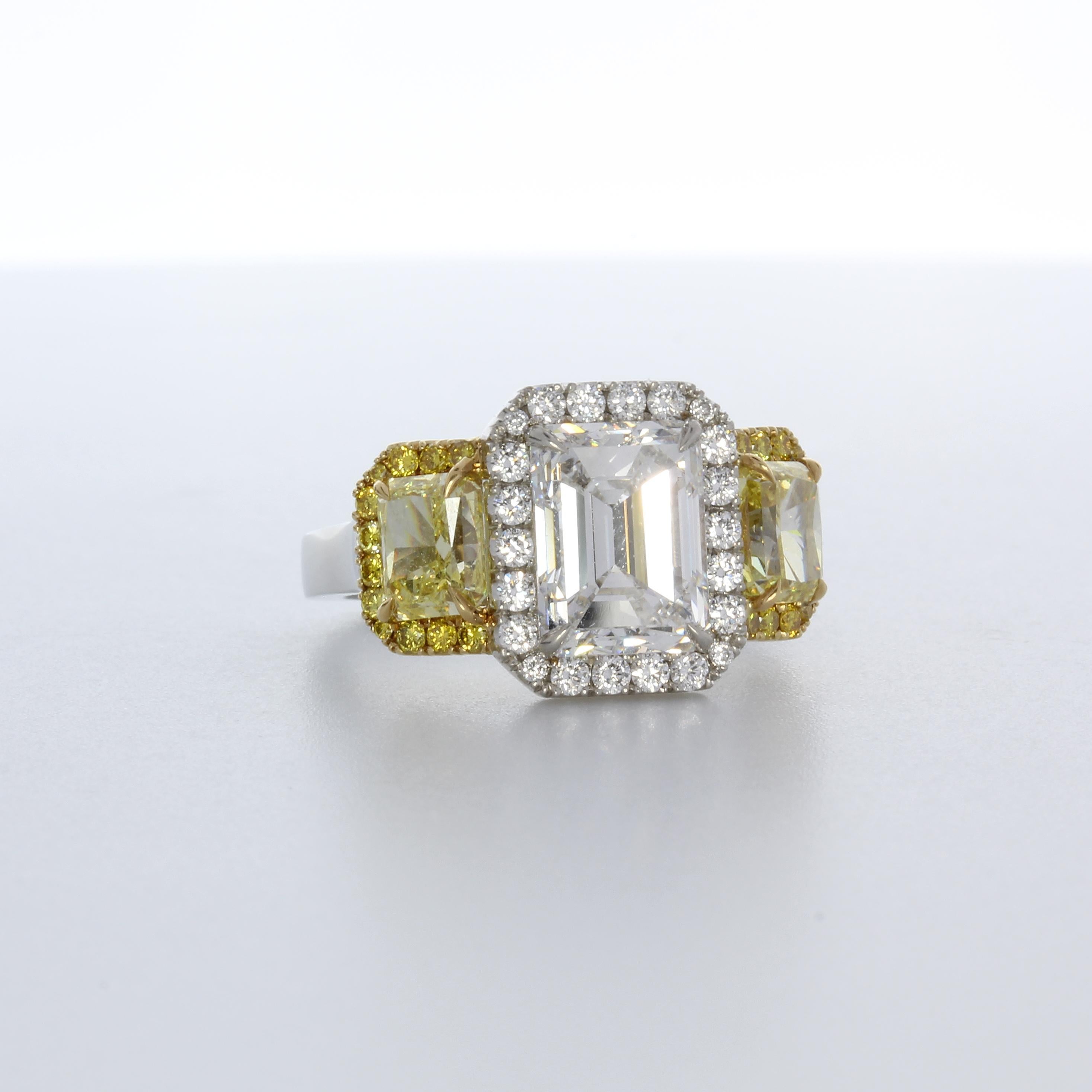 Stunning emerald cut diamond that weighs 3.04 carats flanked with two fancy intense yellow diamonds that total 1.94 carats. Intricate micro-bead setting with brilliant diamonds and 24 fancy yellow diamonds. Crafted in platinum and 18k yellow gold.