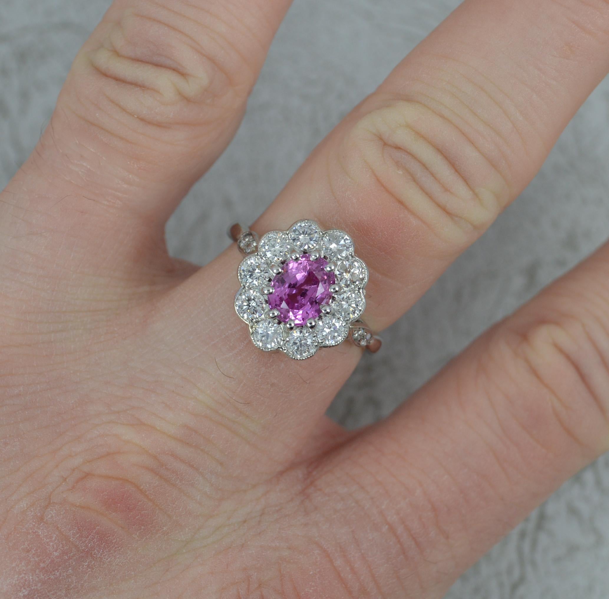 A stunning Pink Sapphire and Diamond cluster ring.
Solid 950 grade platinum example throughout.
Designed with an oval cut vivid pink sapphire to centre, full bezel setting. 1.45 carats. Surrounding are many ten round brilliant cut diamonds with