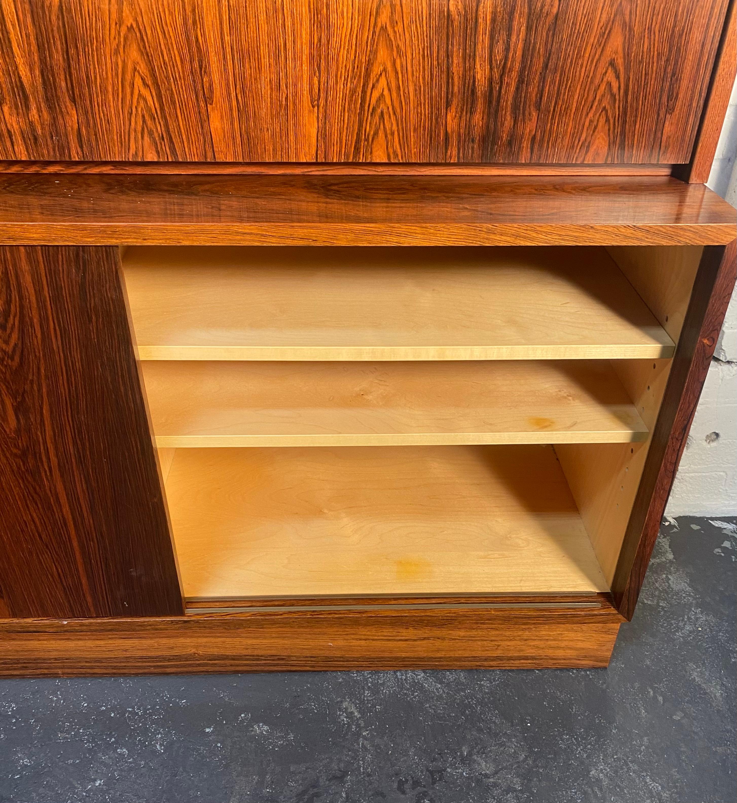 Danish modern, two piece, book matched rosewood, bookcase secretary cabinet by Poul Hundevad ... Birch wood interior,,, features a 26 inch height bottom cabinet with sliding doors, adjustable shelves and green felt lined, pull-out drawer. The 12