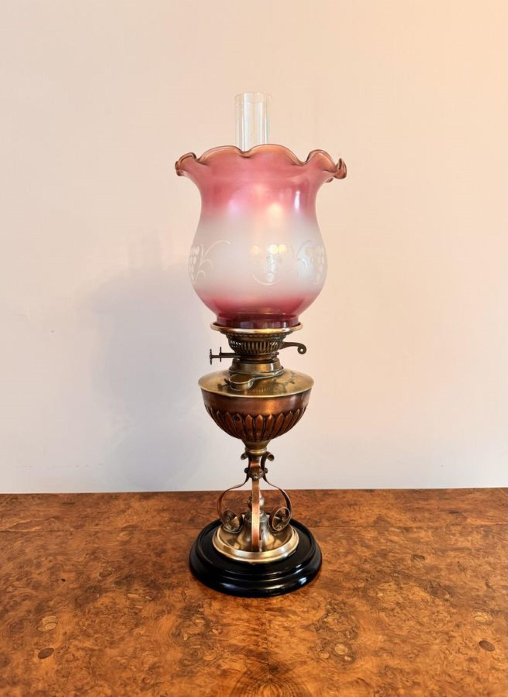 Stunning quality antique arts and crafts brass and copper oil lamp, having the original quality pink glass shade with a wavy shaped edge, a glass chimney, a brass burner, supported by a brass and copper column, raised on a circular base.

D. 1900