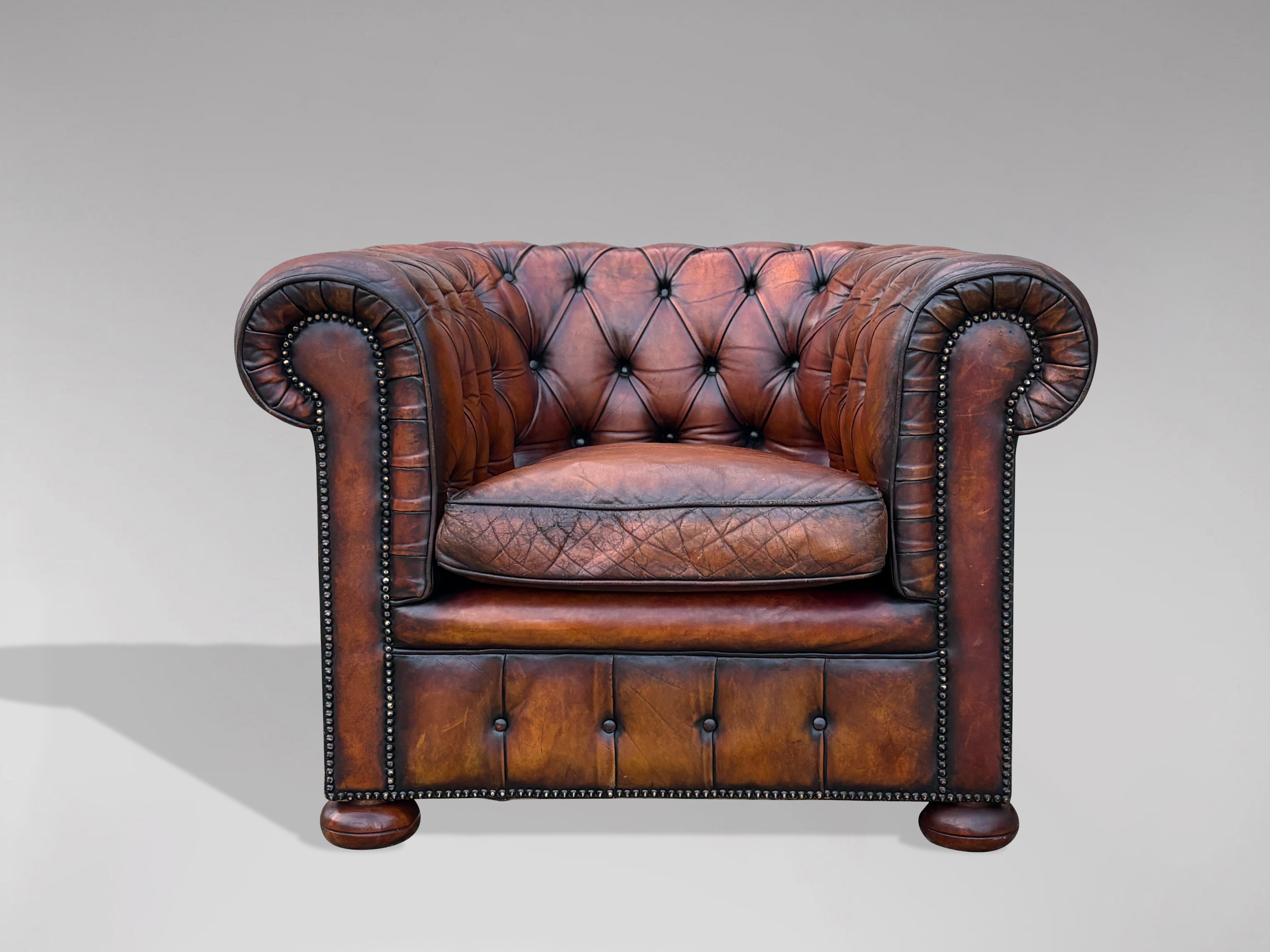 A stunning quality early 20th-century one-seater brown leather Chesterfield with loose feathered cushion, raised on bun feet. It features individually hand-tacked brass studded trim, the padding is the original horse hair. This chesterfield armchair