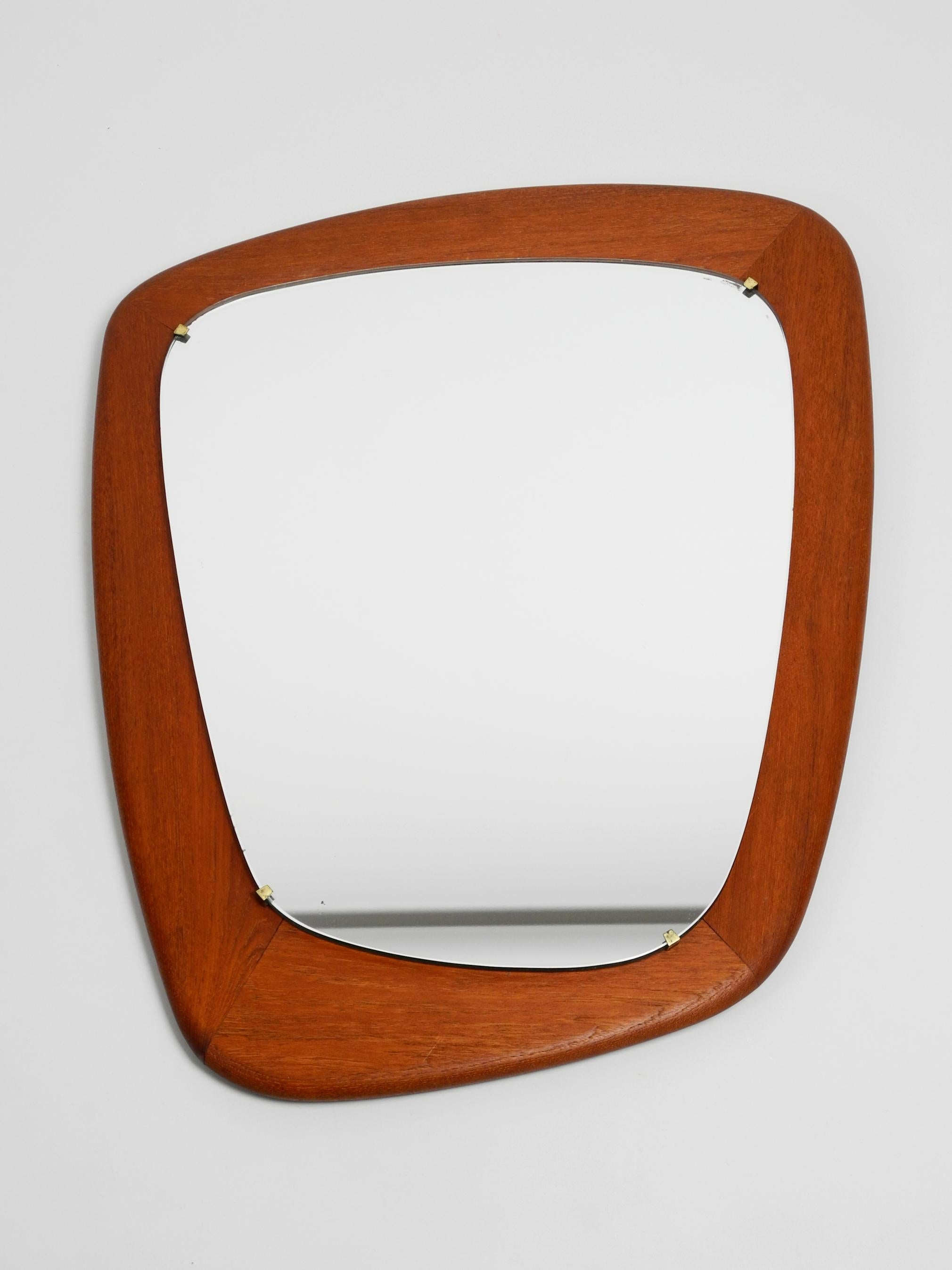 Gorgeous rare large midcentury teak wall mirror.
Very elaborately manufactured, the mirror is made of crystal glass 
and is hold with 4hooks on the outside of the thick frame.
The frame and mirror are built asymmetrically.
High quality