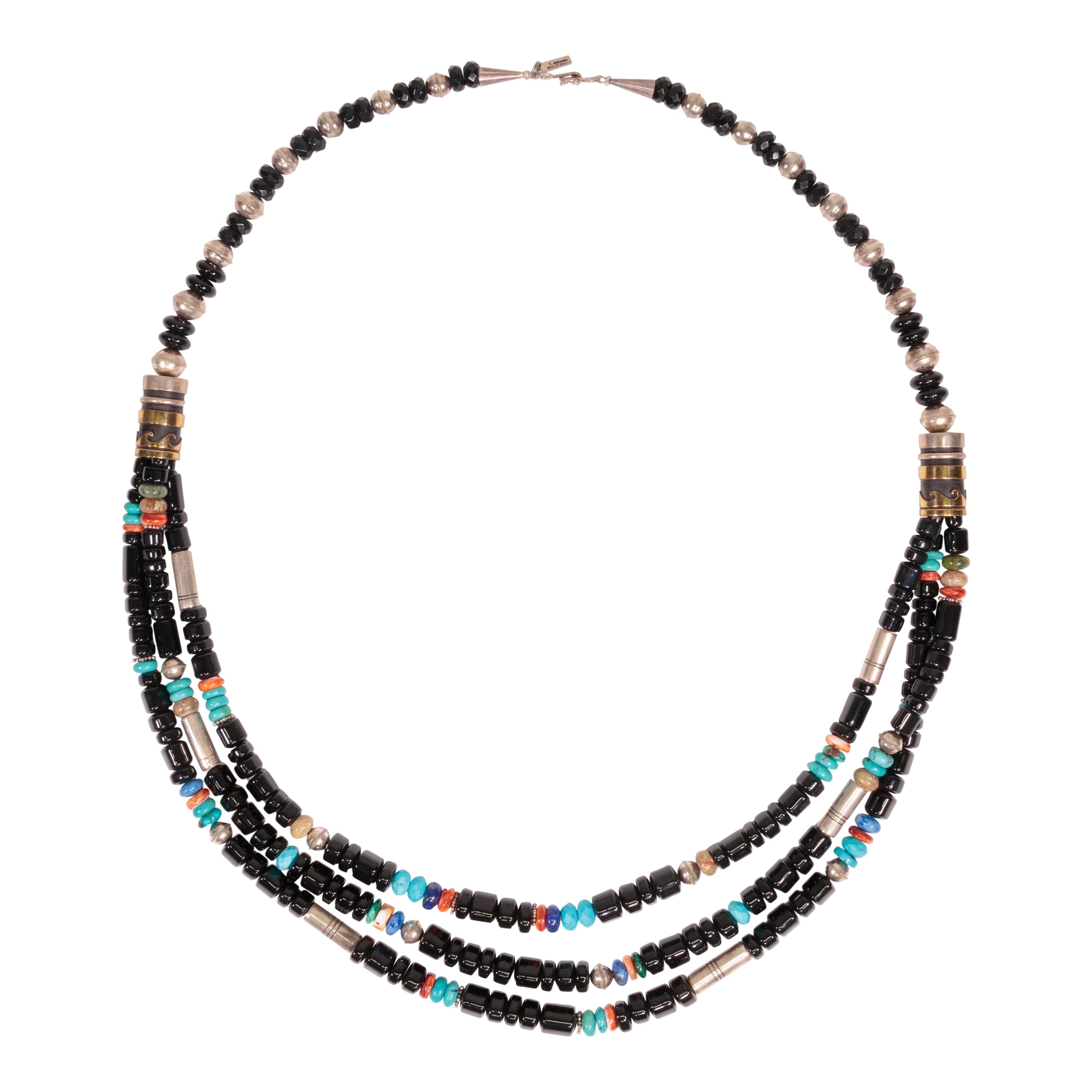 Three-strand necklace signed by Tommy Singer. Onyx tube beads with accent beads of silver and 14k gold, turquoise, spiny oyster, and lapis. Rare and stunning!

Tommy Singer (1940 - May 31, 2014) was a World Famous Navajo Silversmith and his distinct