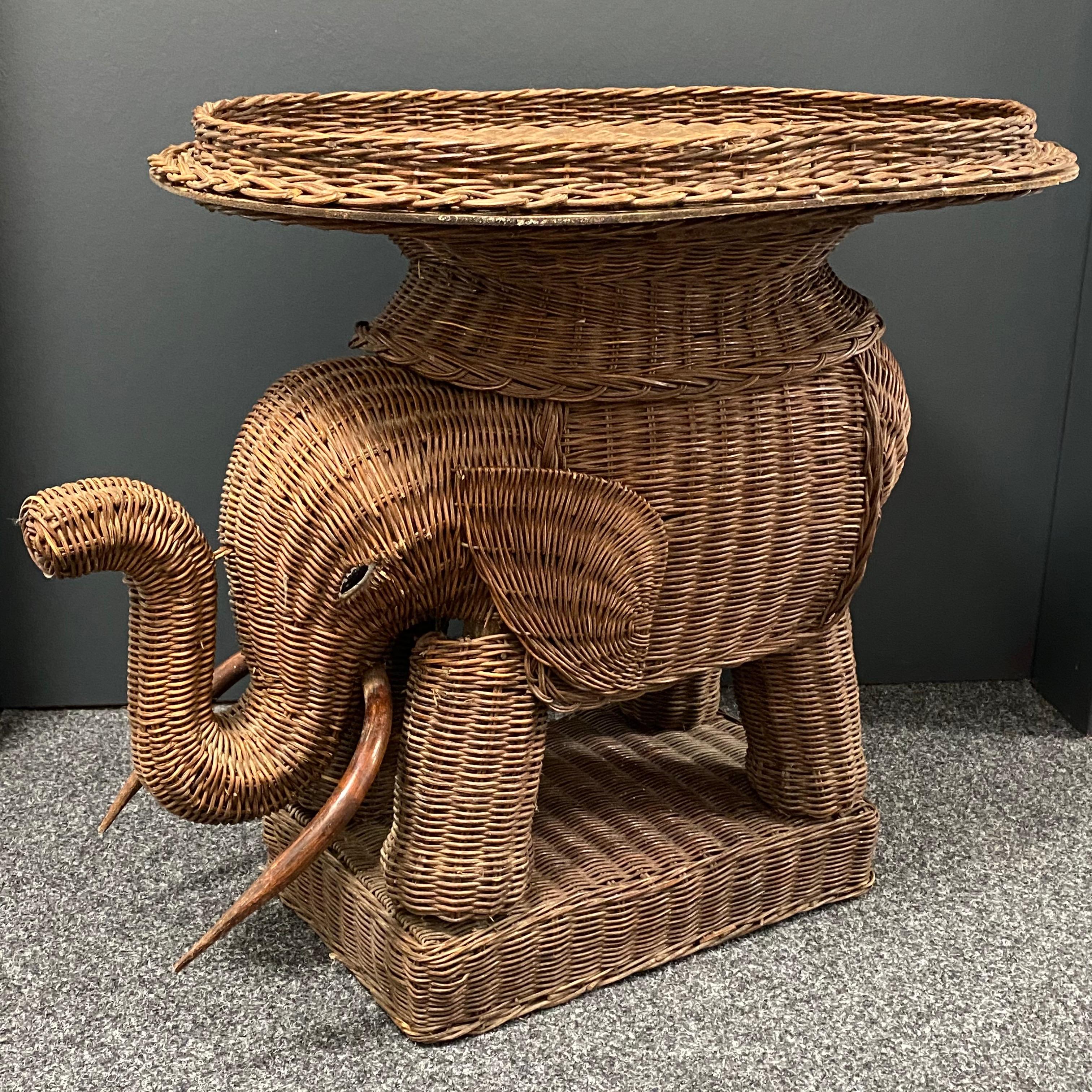 Mid-20th century eye-catching elephant-shaped end table or side table, constructed in hand-braided rattan accented with wood tusks. Nice addition to your home, patio or garden. This is in used condition, with signs of wear as expected with age and