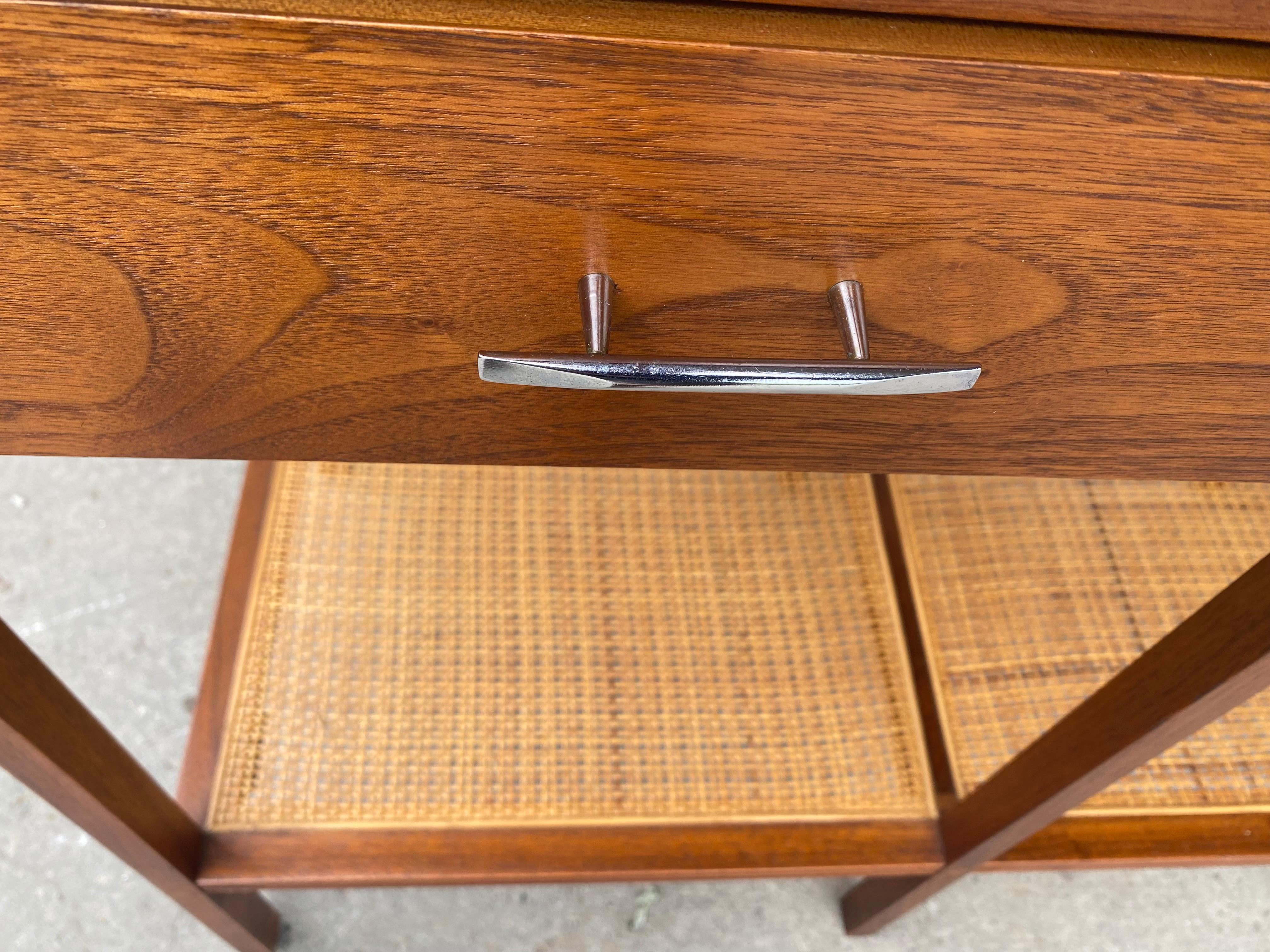 A Paul McCobb design for Lane, from his Delineator line.
This is the rare console table, stunning walnut with rosewood, richly grained, book matched, three drawers and a cane lower shelf.
Amazing original condition, retains origin label. As well