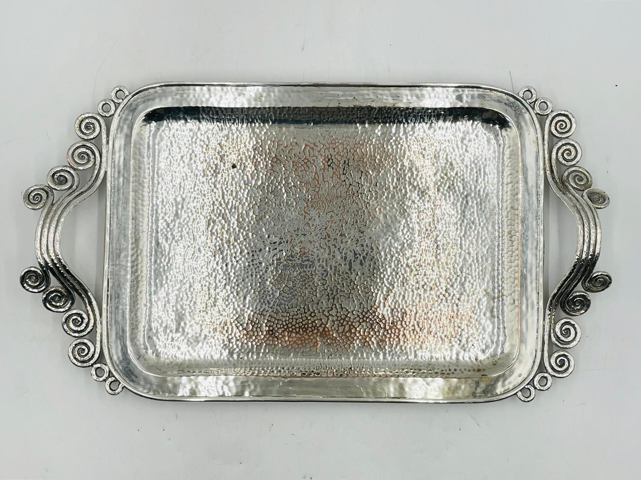 Eleva tu experiencia gastronómica con esta exquisita e impresionante Bandeja para servir chapada en plata, diseñada y fabricada en Taxco, México, por Emilia Castillo, artesana de México en la década de 1980. 
La pieza está hecha de cobre macizo