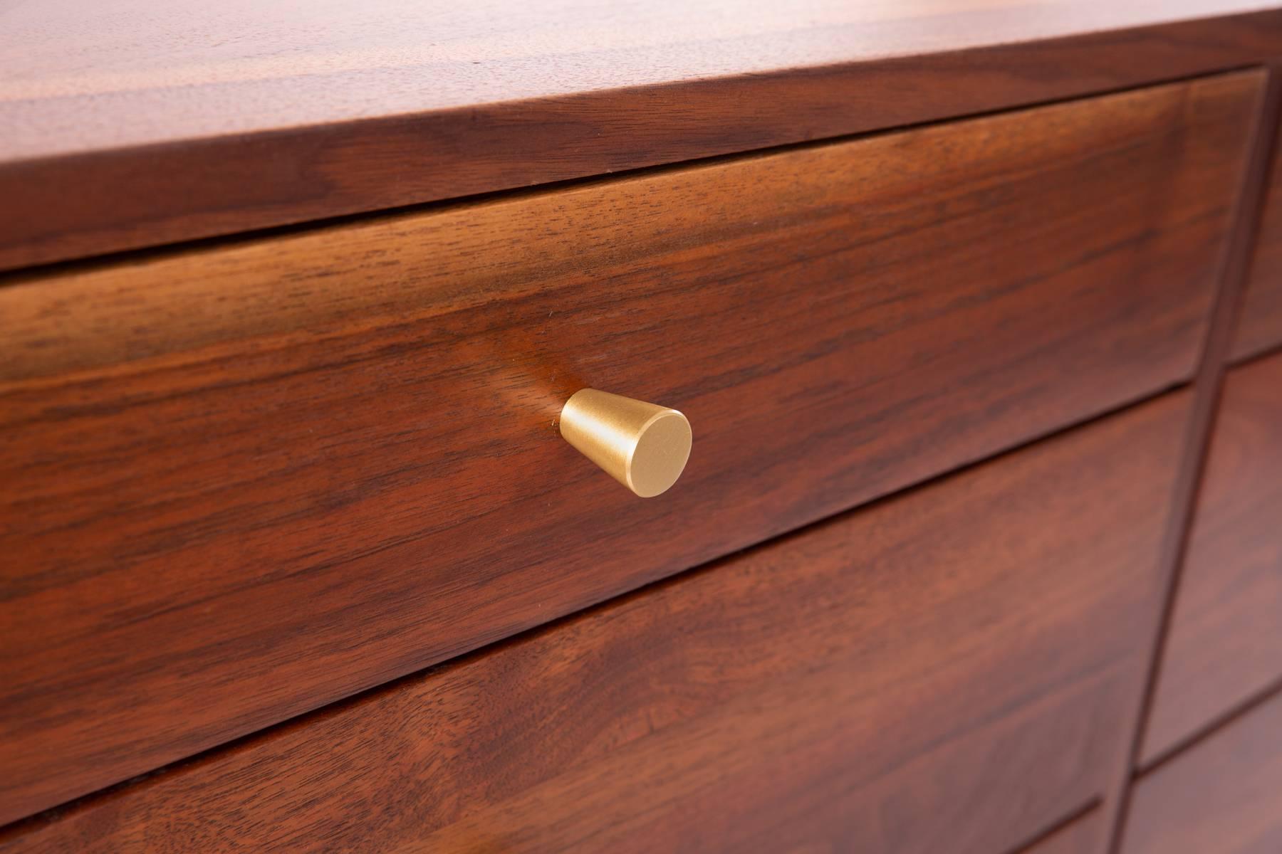 Solid walnut and brass 12-drawer dresser, circa late 1950s. This example has incredibly grained walnut with a large amount of sap grain. The drawer pulls are solid satin finished brass which highlight the walnut beautifully.