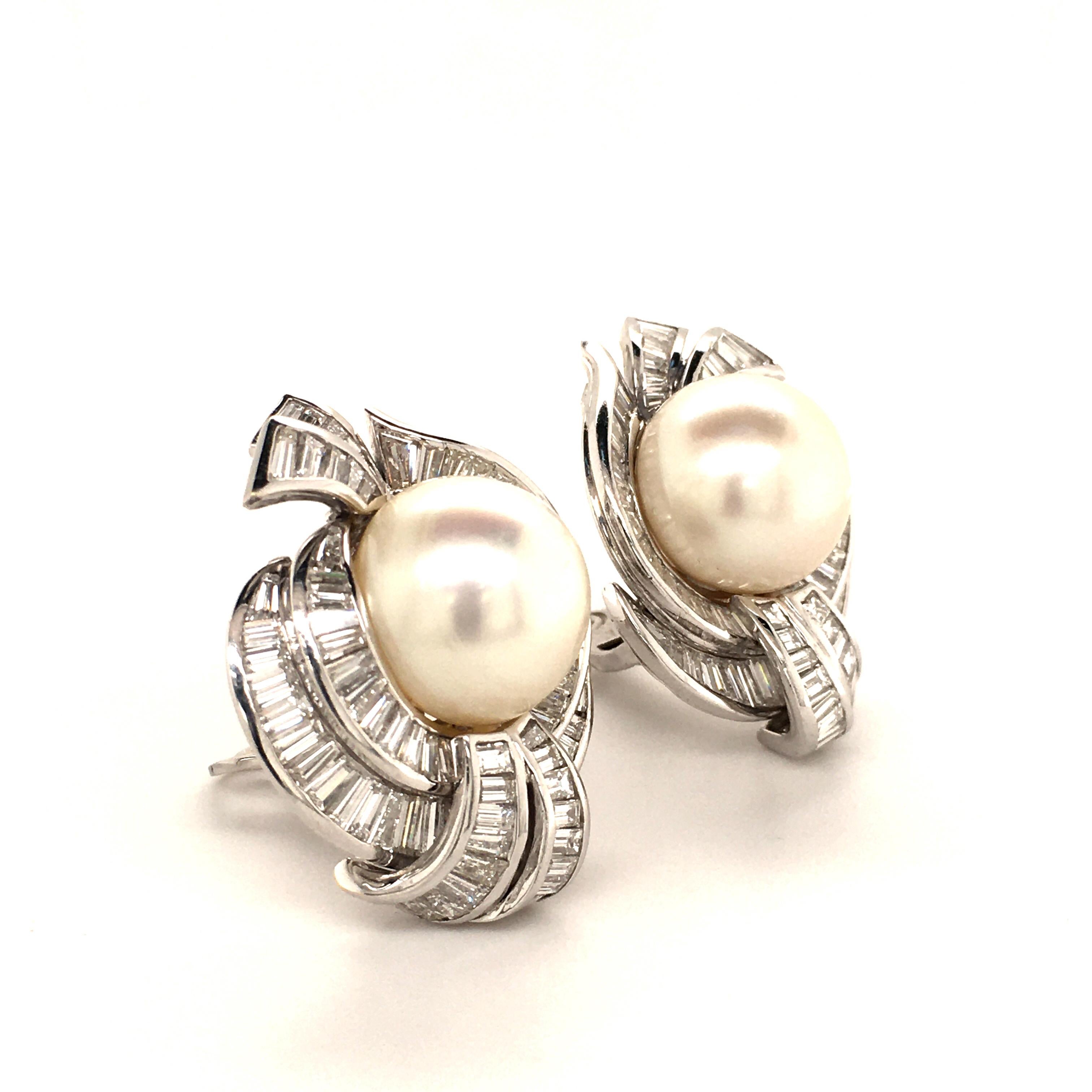 What a show! Spectacular pair of Cultured South Sea Pearls of 16 mm in diameter. Slightly button shaped, white and with a great luster. Double entourage of 12 carats in baguette- and tapered-cut diamonds placed in a channel setting. Interrupted by