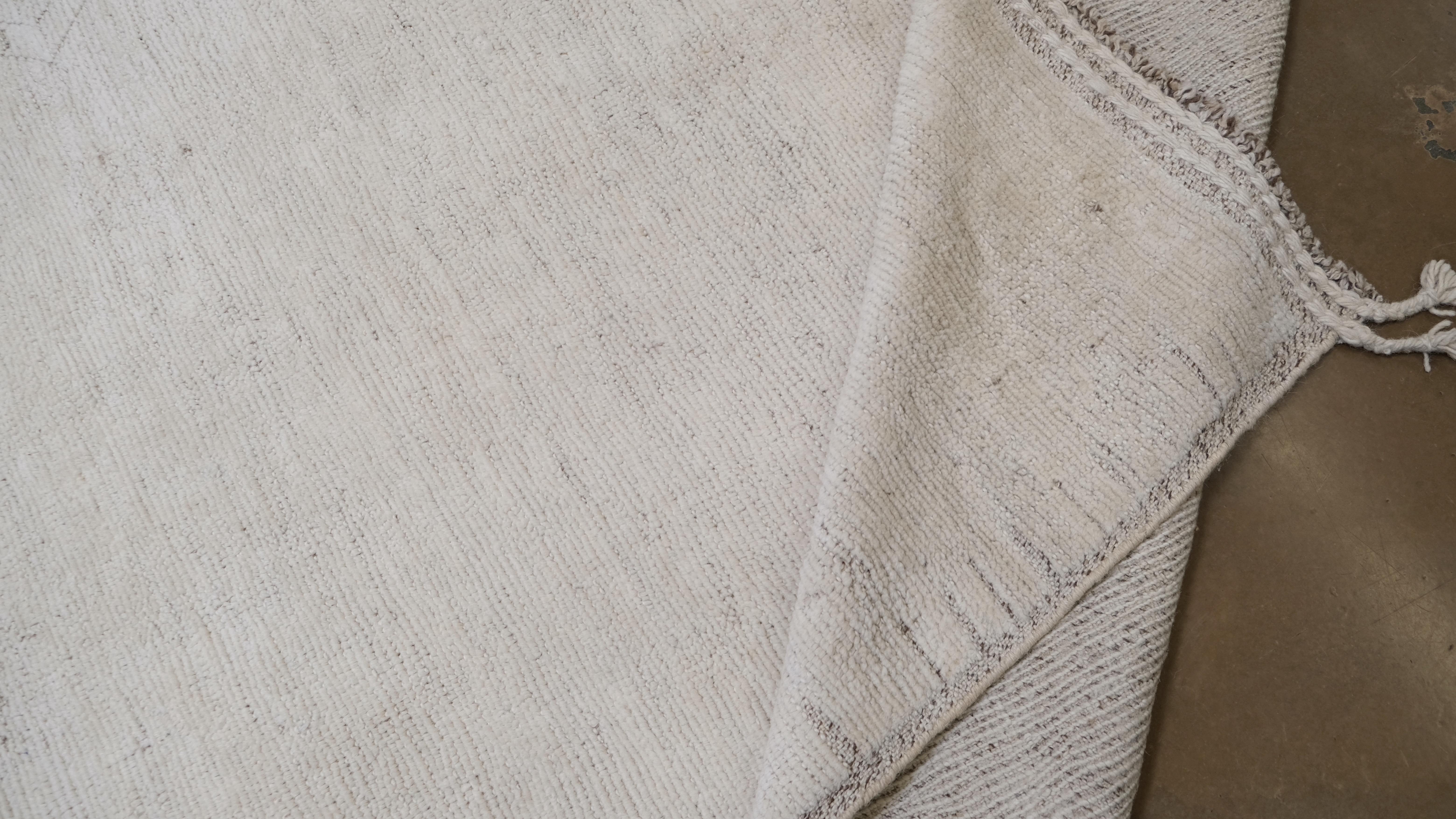 Bringen Sie mit diesem modernen, handgeknüpften Wollteppich aus Pakistan schlichte Eleganz in Ihr Zuhause. Das Design mit seinem subtilen, aber raffinierten geometrischen Muster ist eine meisterhafte Mischung aus Minimalismus und Kunstfertigkeit,