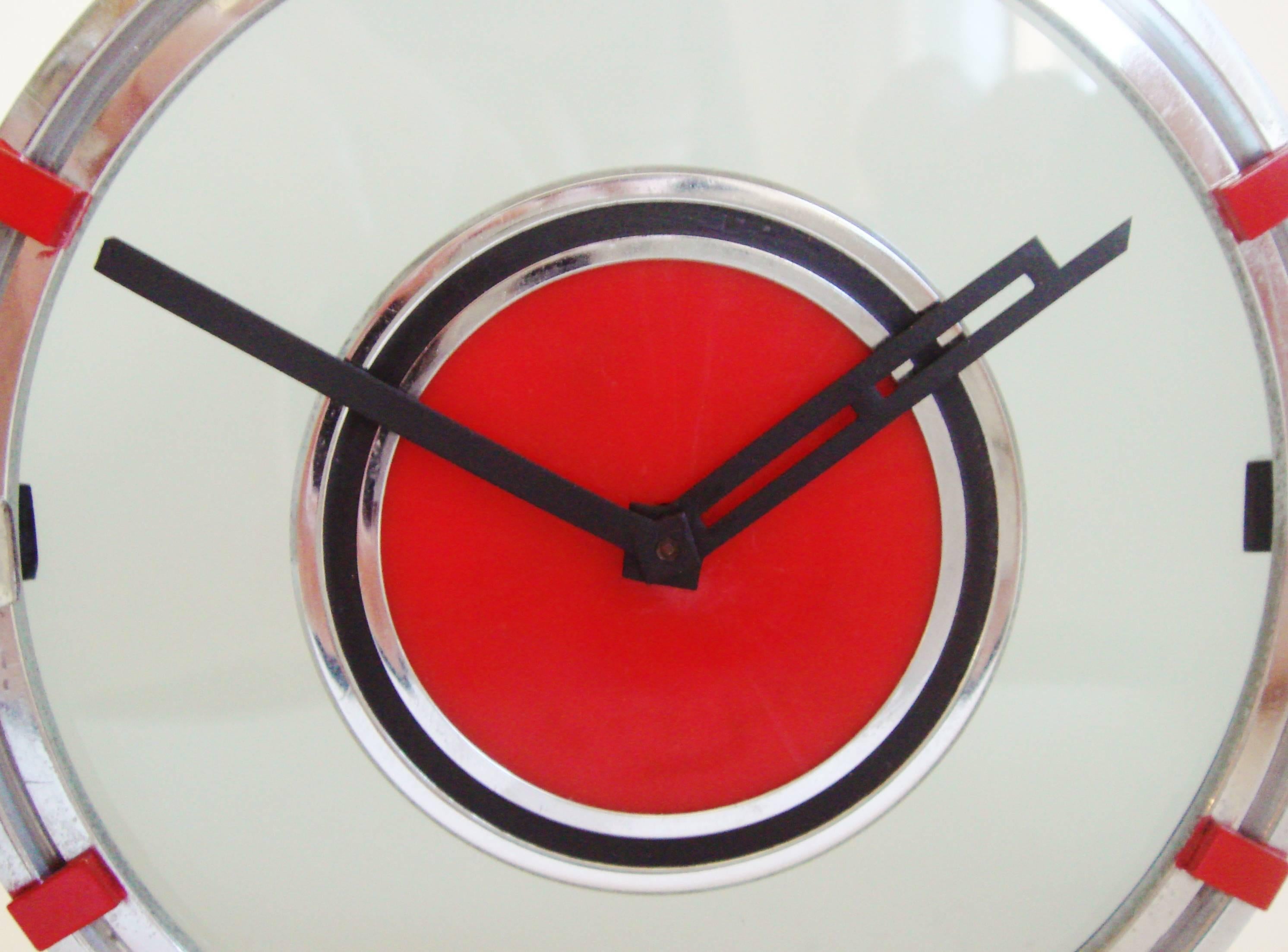 This stunningly designed, museum quality, Swiss Art Deco chrome, black enamel and red Phenolic desk clock is by the Movado company. It features an overall cloud shaped profile with a tinted glass face and a chrome bezel accented with red enameled