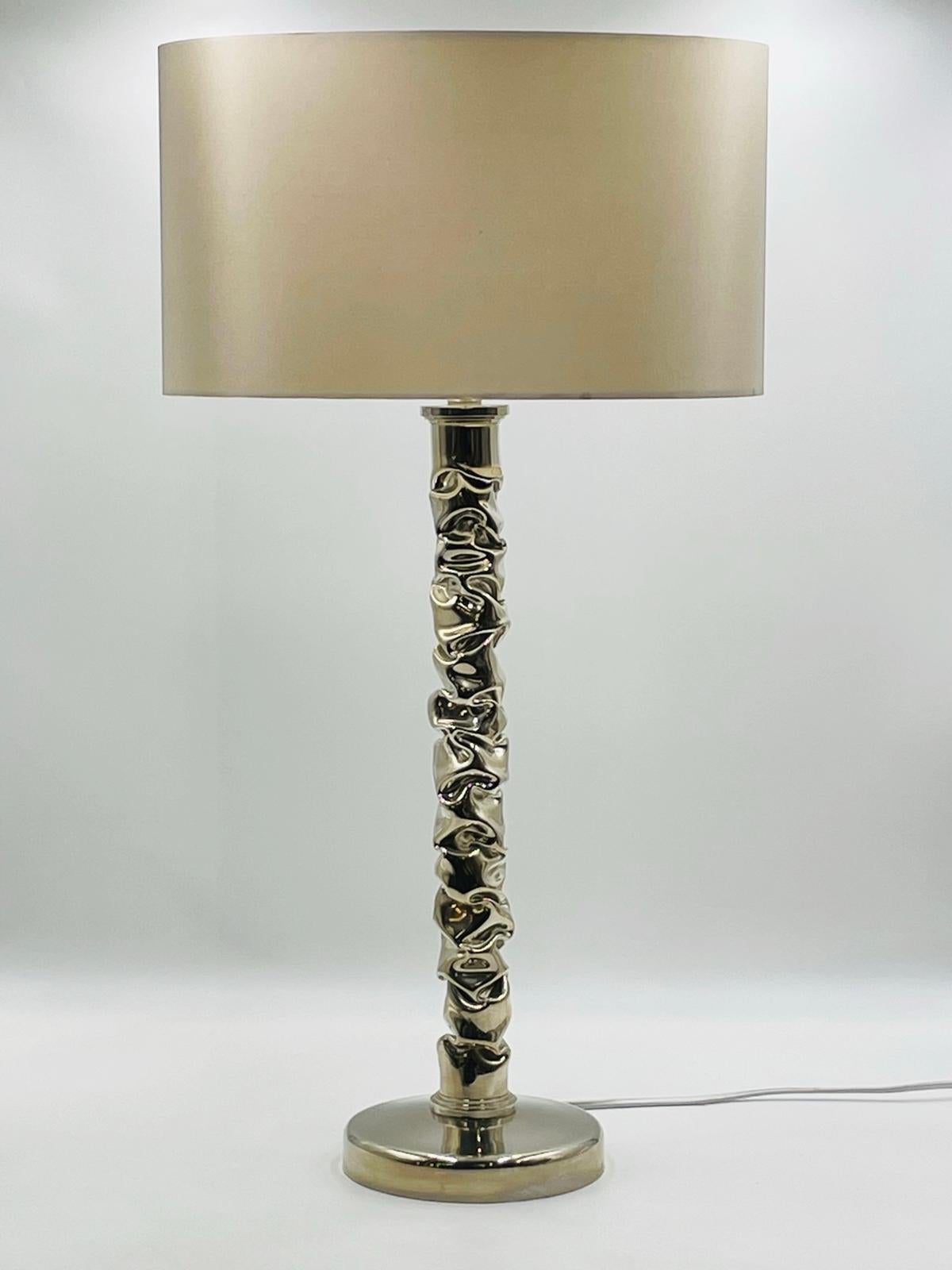 Introducing the stunning table lamp in polished nickel, made by the renowned British furniture company Porta Romana. Crafted with meticulous attention to detail, this lamp features a sleek metal base with a polished nickel finish, exuding an elegant